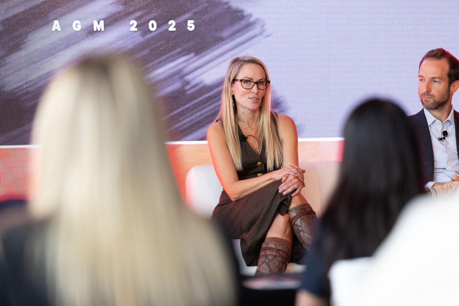 Blonde woman in glasses speaks on stage at AOM 2025 annual conference panel discussion.