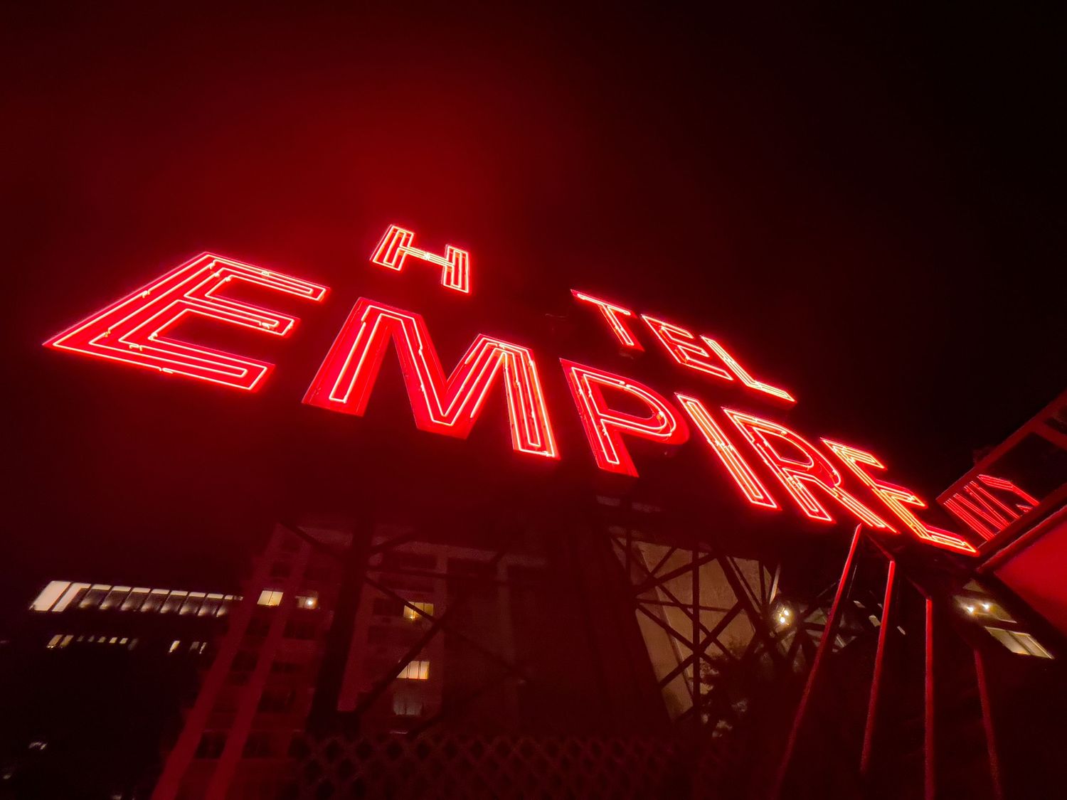 Red neon Hotel Empire sign glowing brightly against a dark night sky.