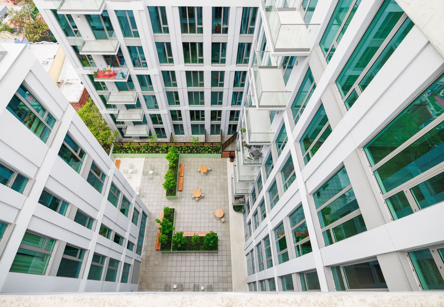 Aerial view of a white residential building courtyard with outdoor seating and green wall accents.