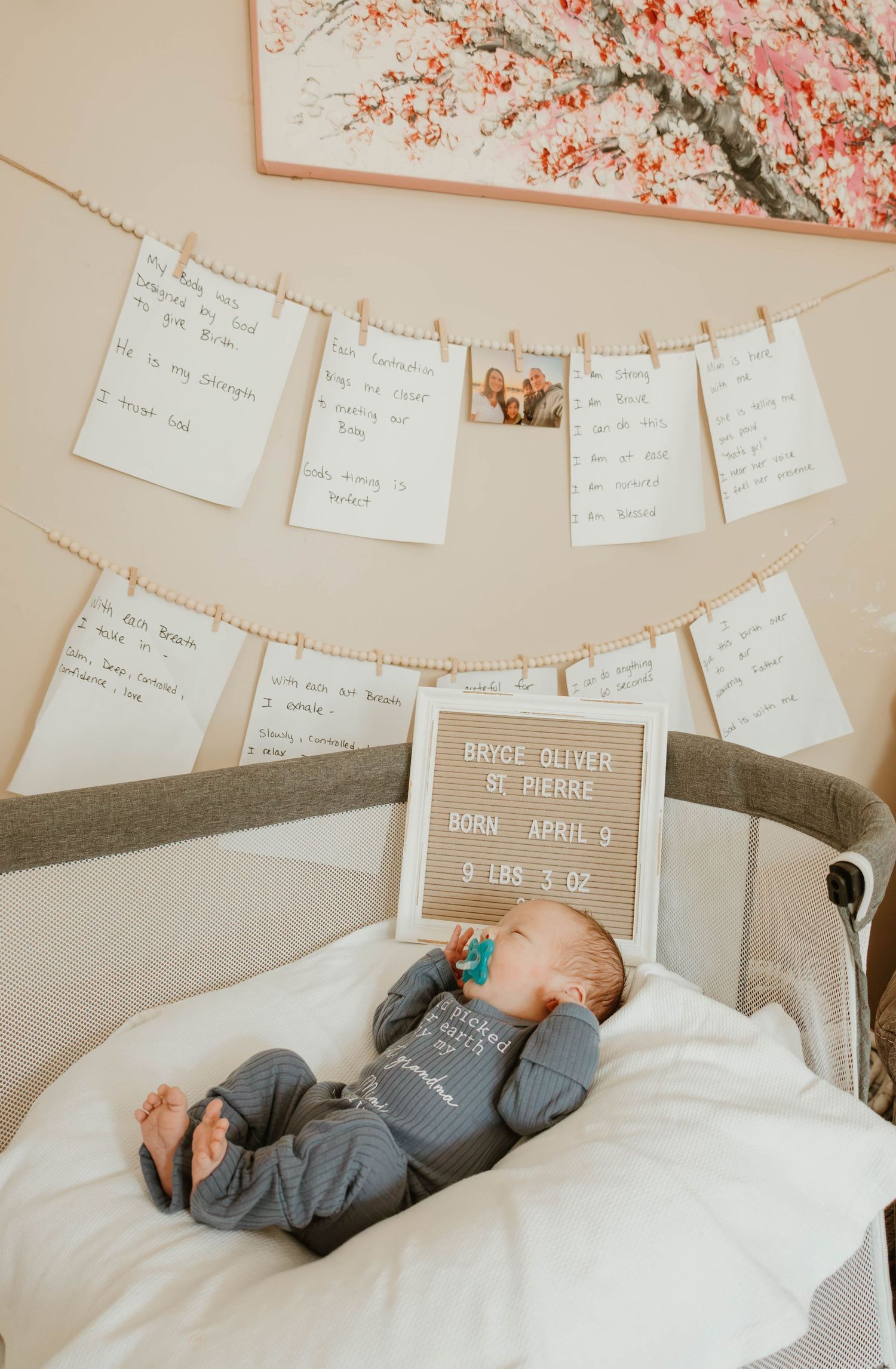 Newborn baby boy Bryce Oliver St. Pierre, born April 9, 9lbs 3oz, lying in crib with handwritten notes on wall.