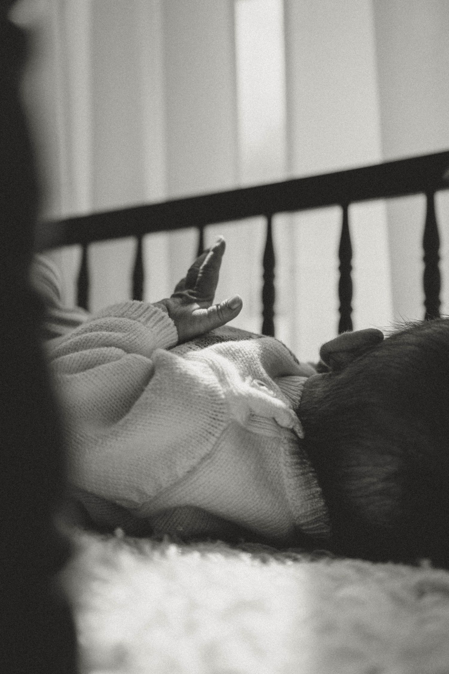A close-up black and white image shows a person's hand resting on a soft, textured surface.