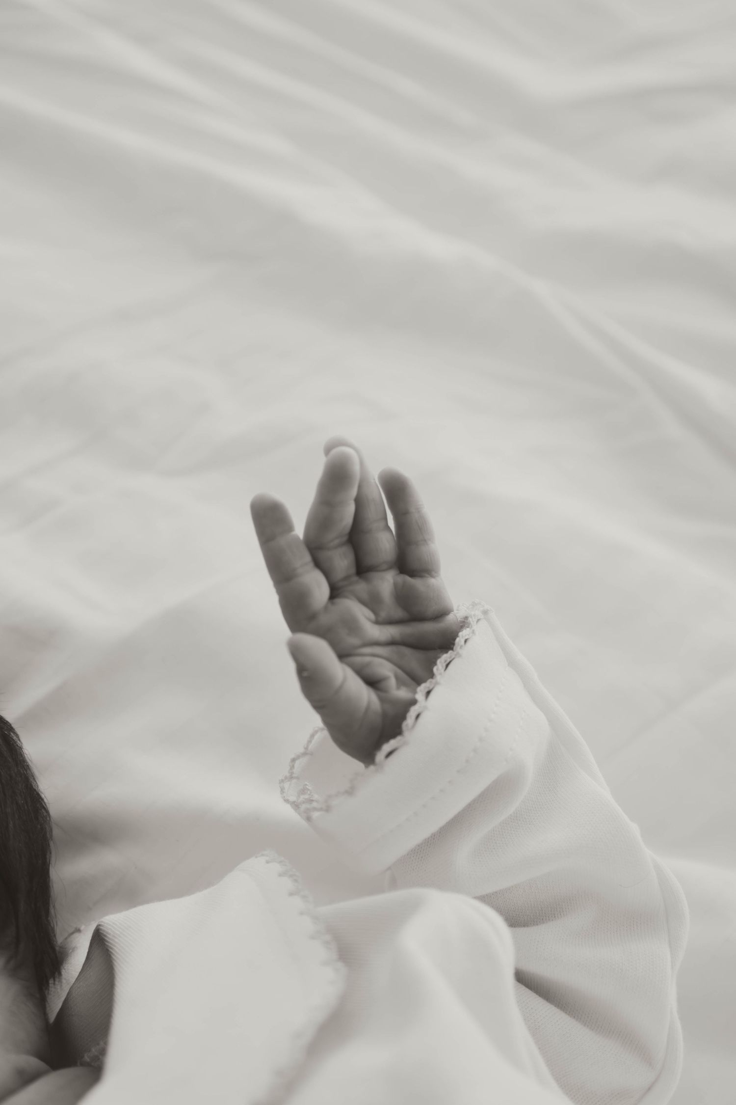 A series of black and white photographs showing a hand emerging from white fabric in different positions.