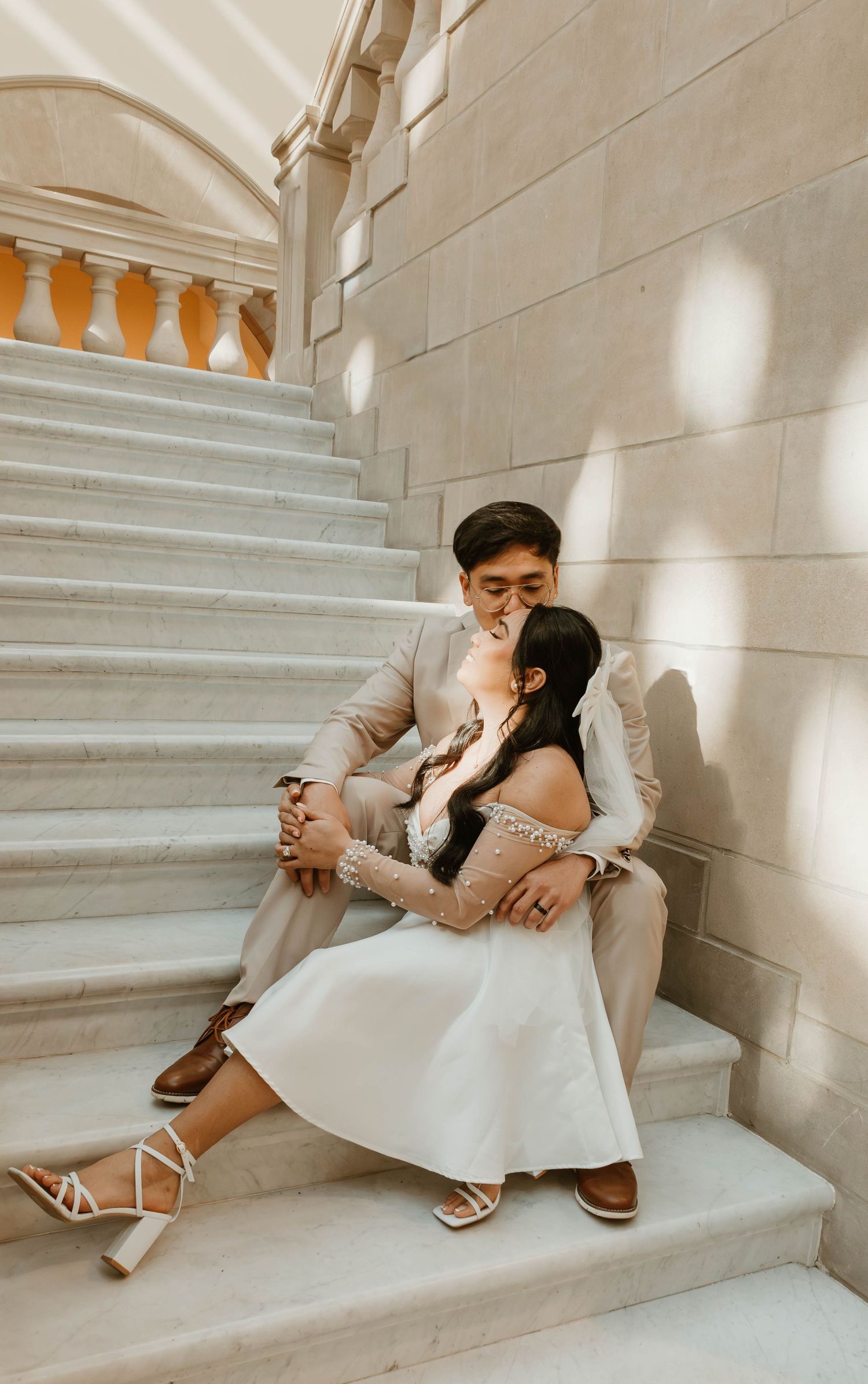 The image shows a couple sitting on stairs, with the woman resting her head on the man's shoulder.
