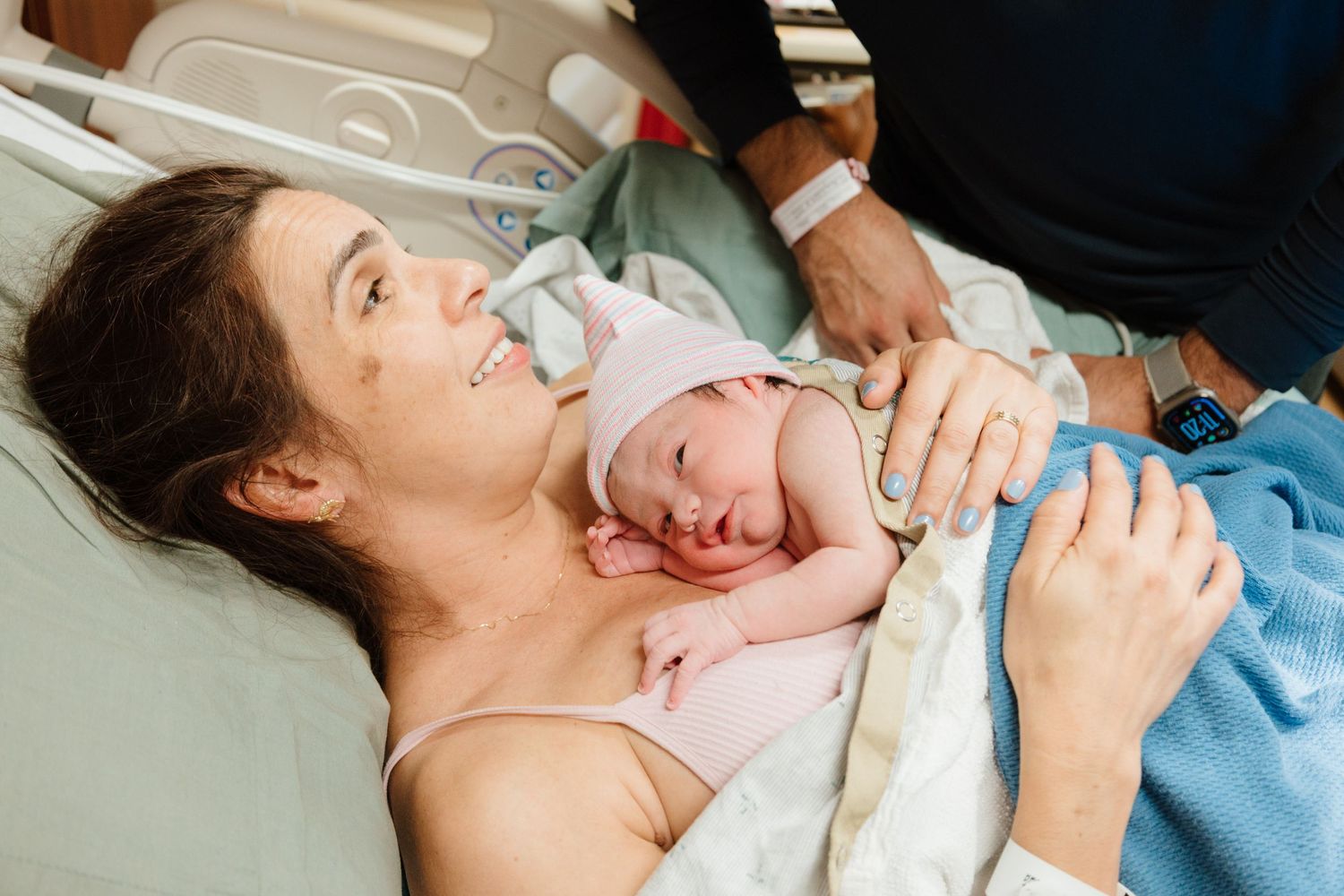 Hospital staff providing care to newborn baby in medical setting.