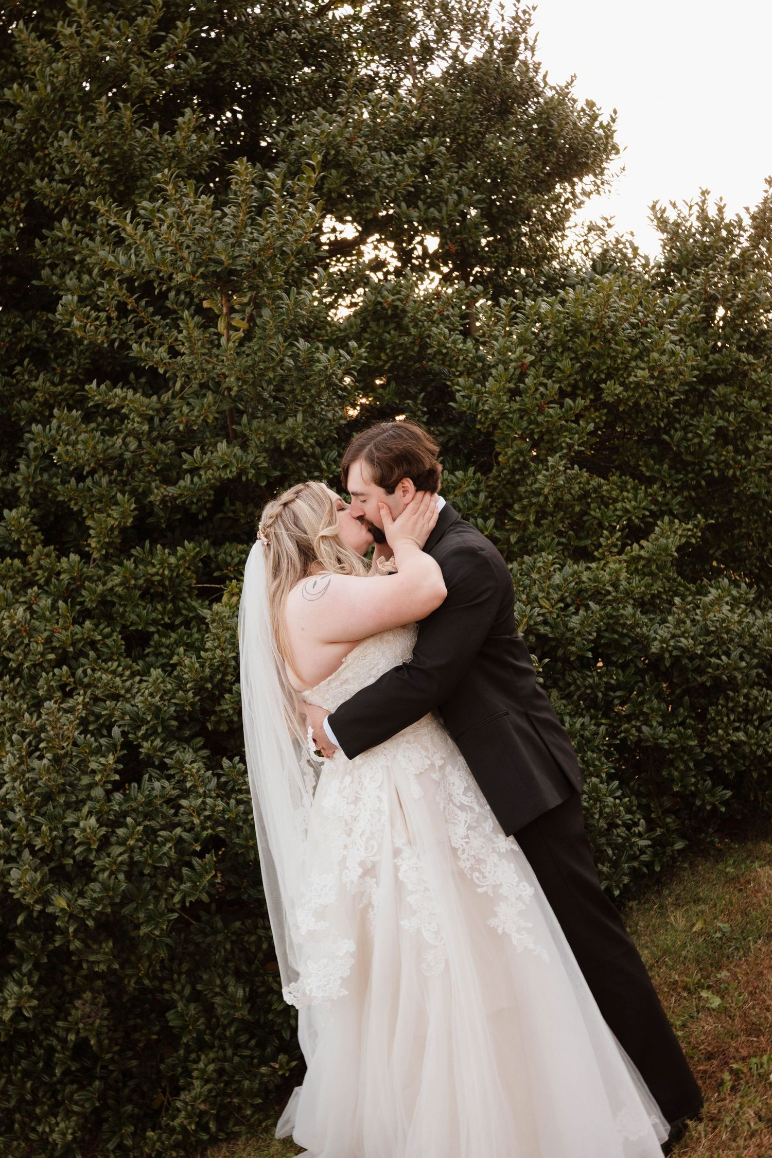Romantic moment between newlyweds against a backdrop of lush green foliage.