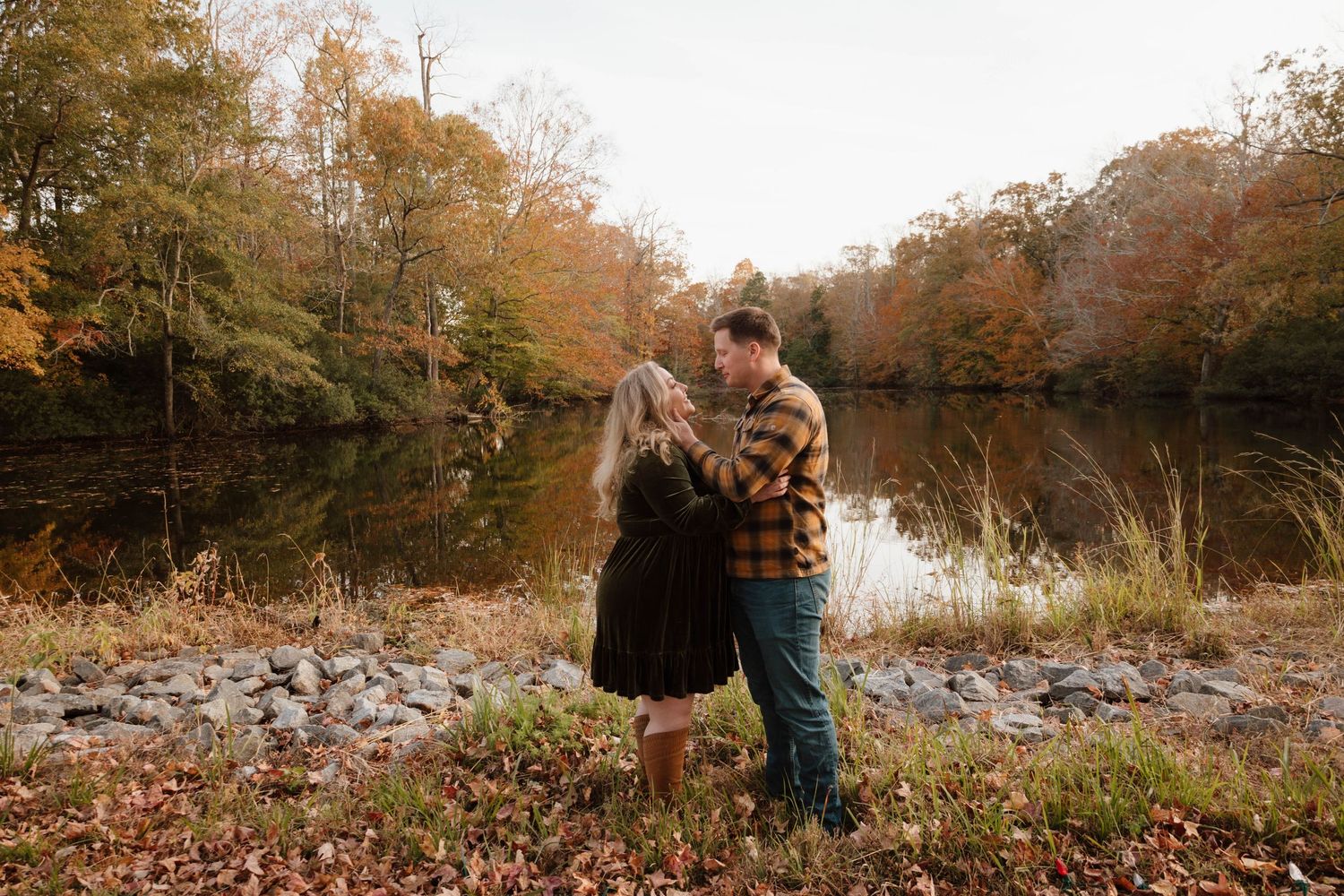 Couple walking through a rocky autumn landscape near water.
