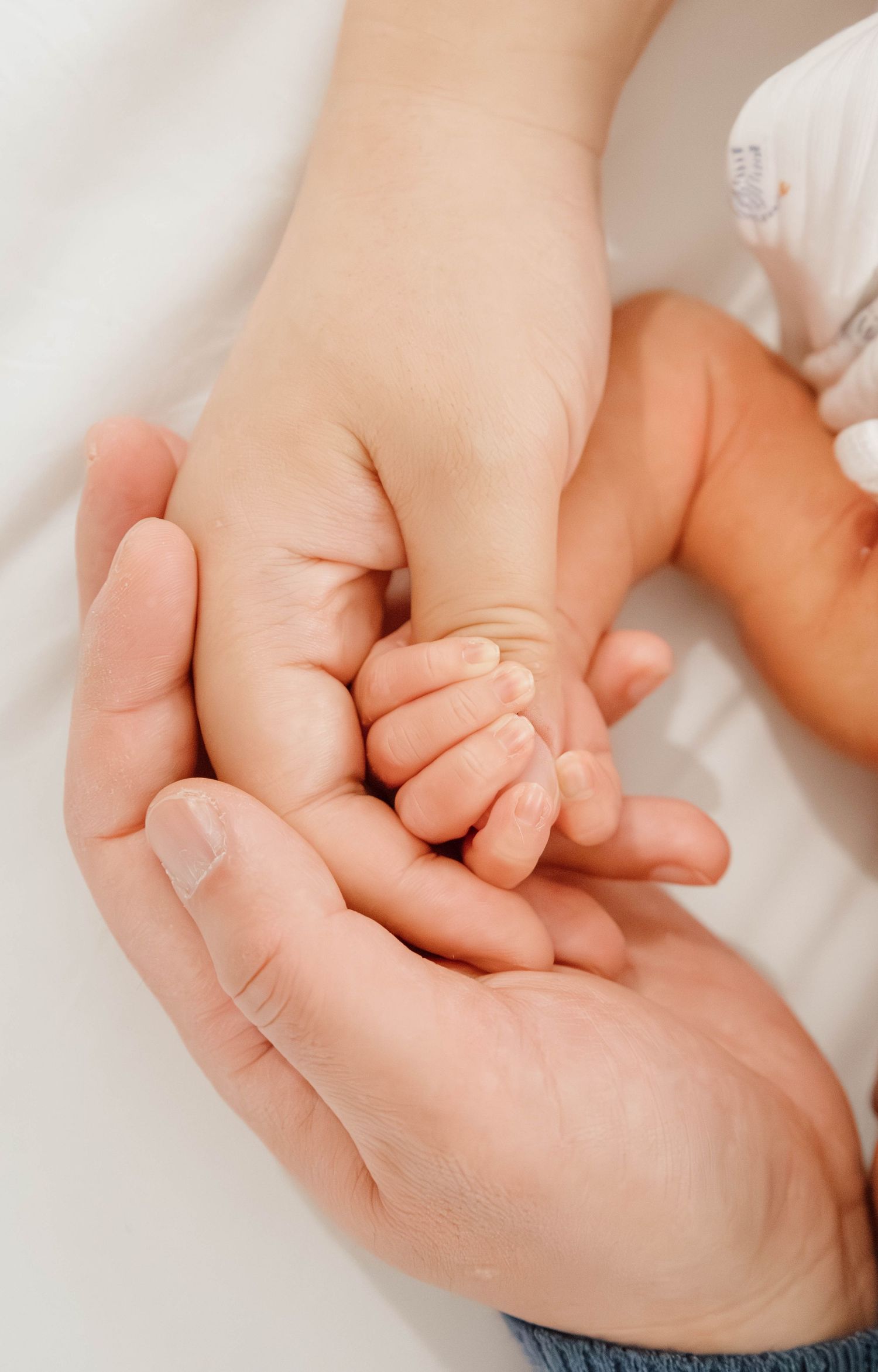 Gentle close-up of baby's tiny hand holding parent's finger.