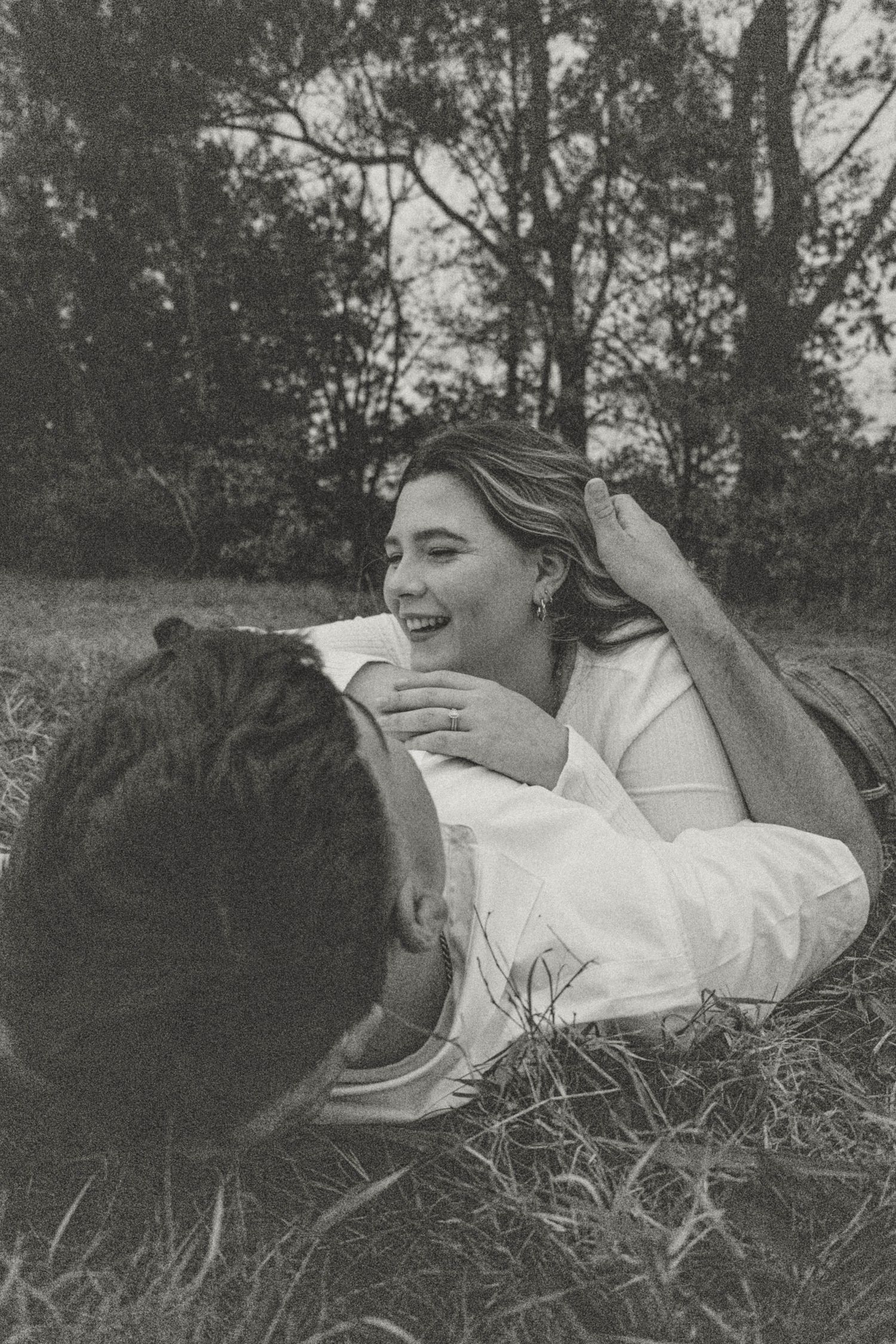 A black and white photo of a couple lying in grass during an intimate moment.