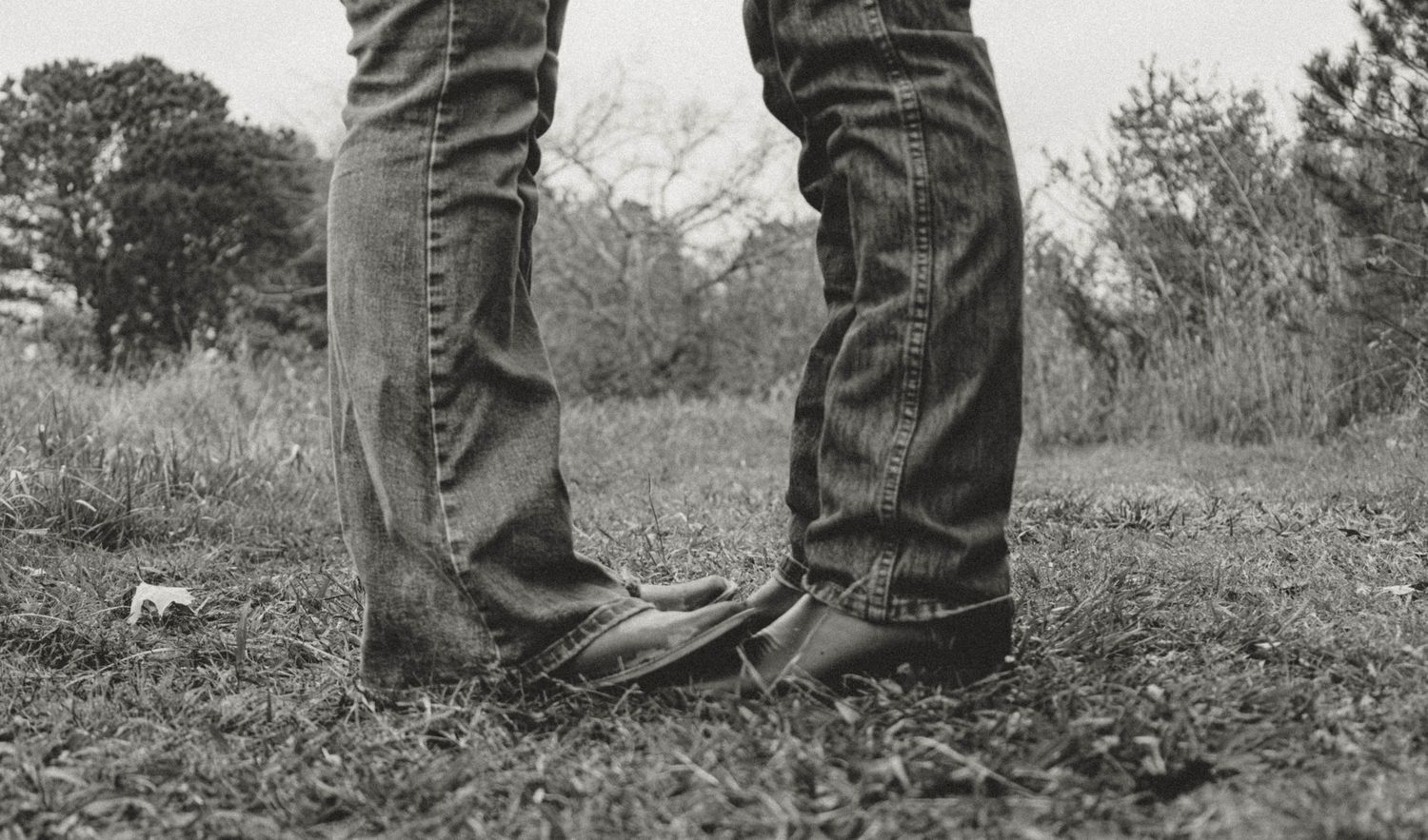 Close-up view of denim-clad legs standing together outdoors.
