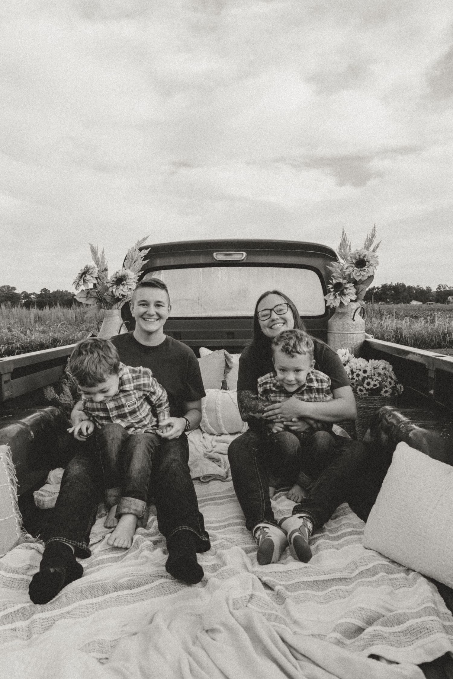 Black and white family photos taken in vintage truck bed showing joyful expressions and laughter.