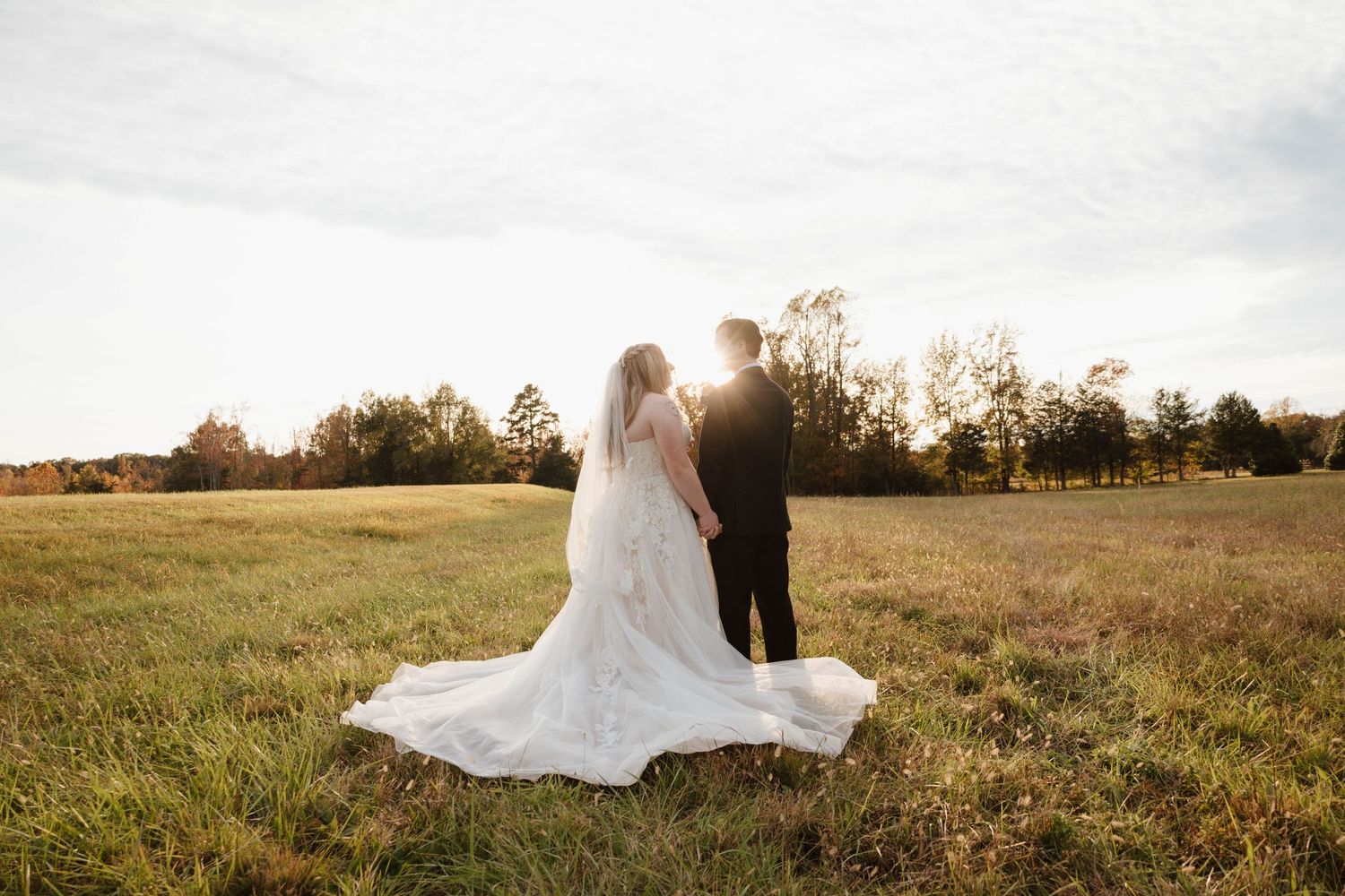 Panoramic view of a couple walking through an open field during their autumn wedding.
