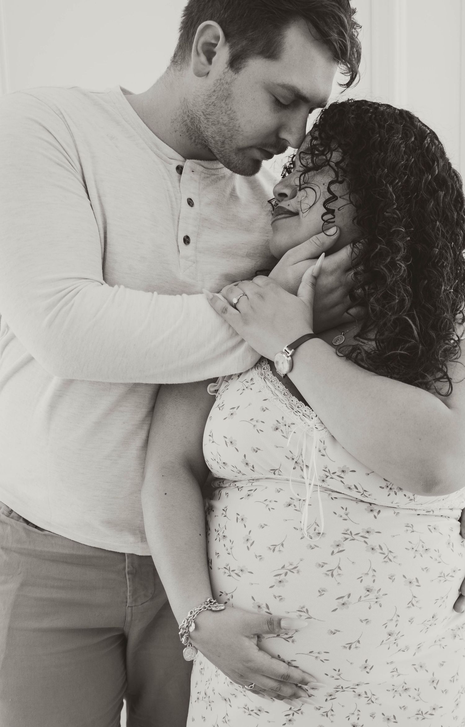 A man tenderly embracing a woman with curly hair in a black and white photograph.