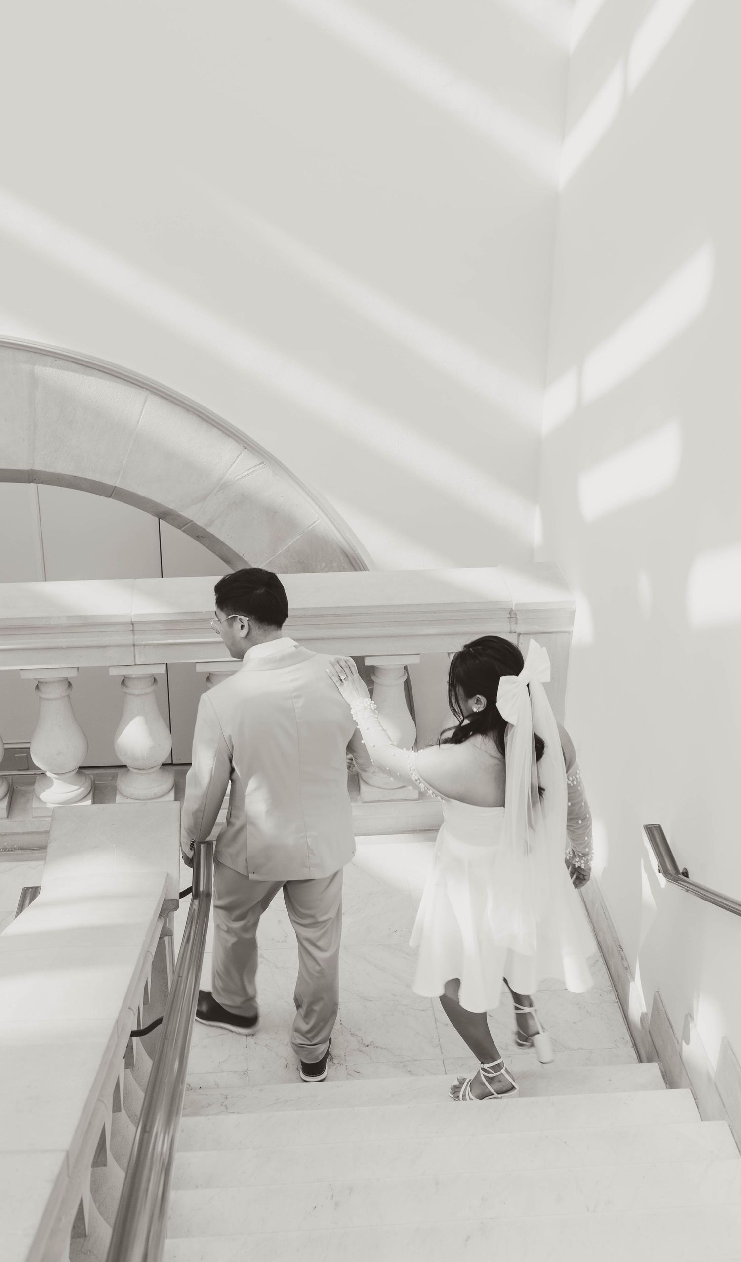 A couple walks up stairs in a modern, minimalist architectural setting.