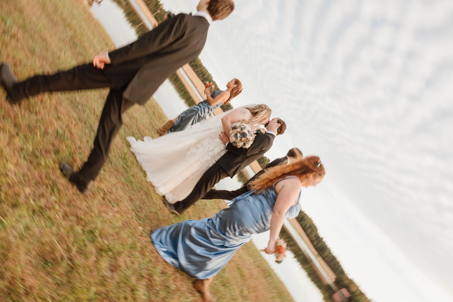 Wedding party celebrates on a wooden deck overlooking a scenic landscape.