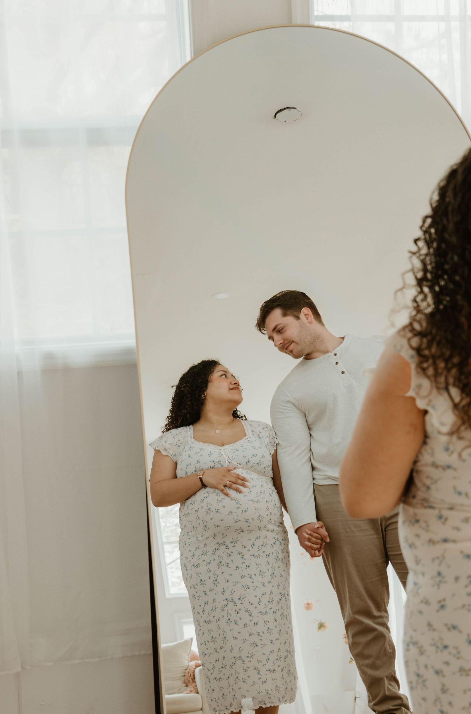 A couple standing together and embracing in a bright, airy room.