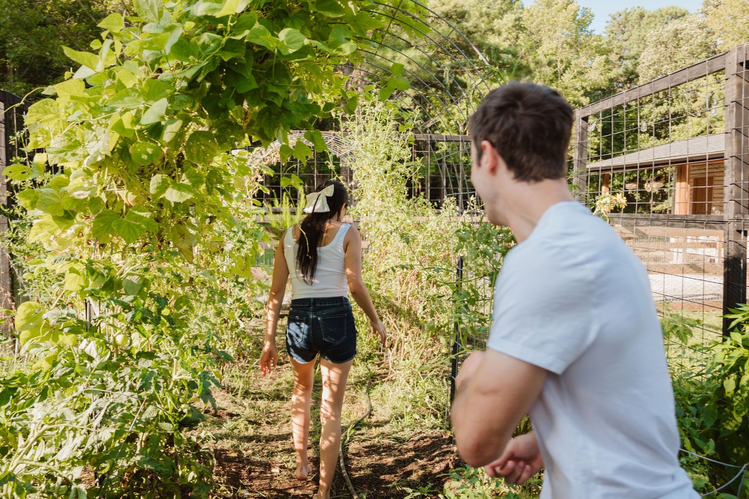 Person walking ahead on garden path while being photographed from behind.