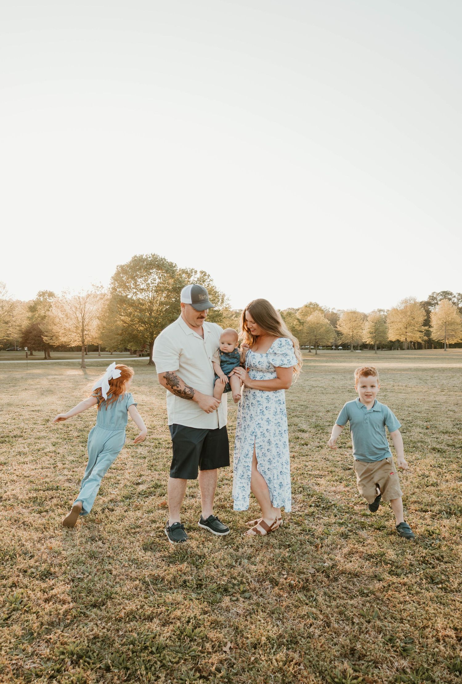Family of five enjoying a golden hour outdoor photo session in a sunny open field.