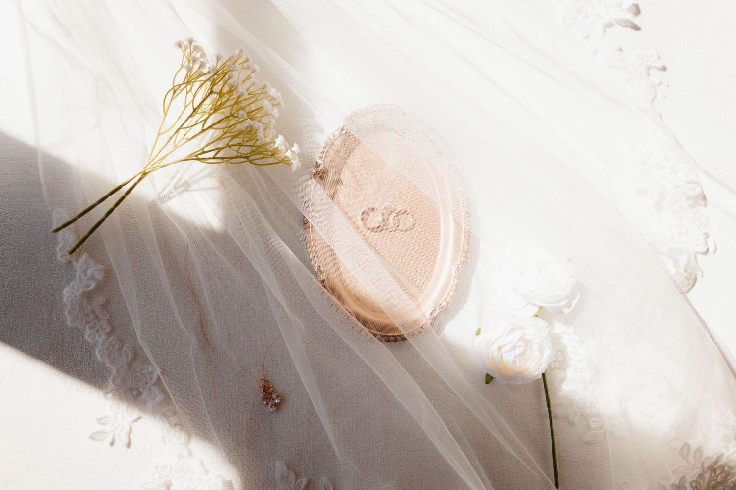 Delicate wedding details with white tulle and golden accents in soft lighting.