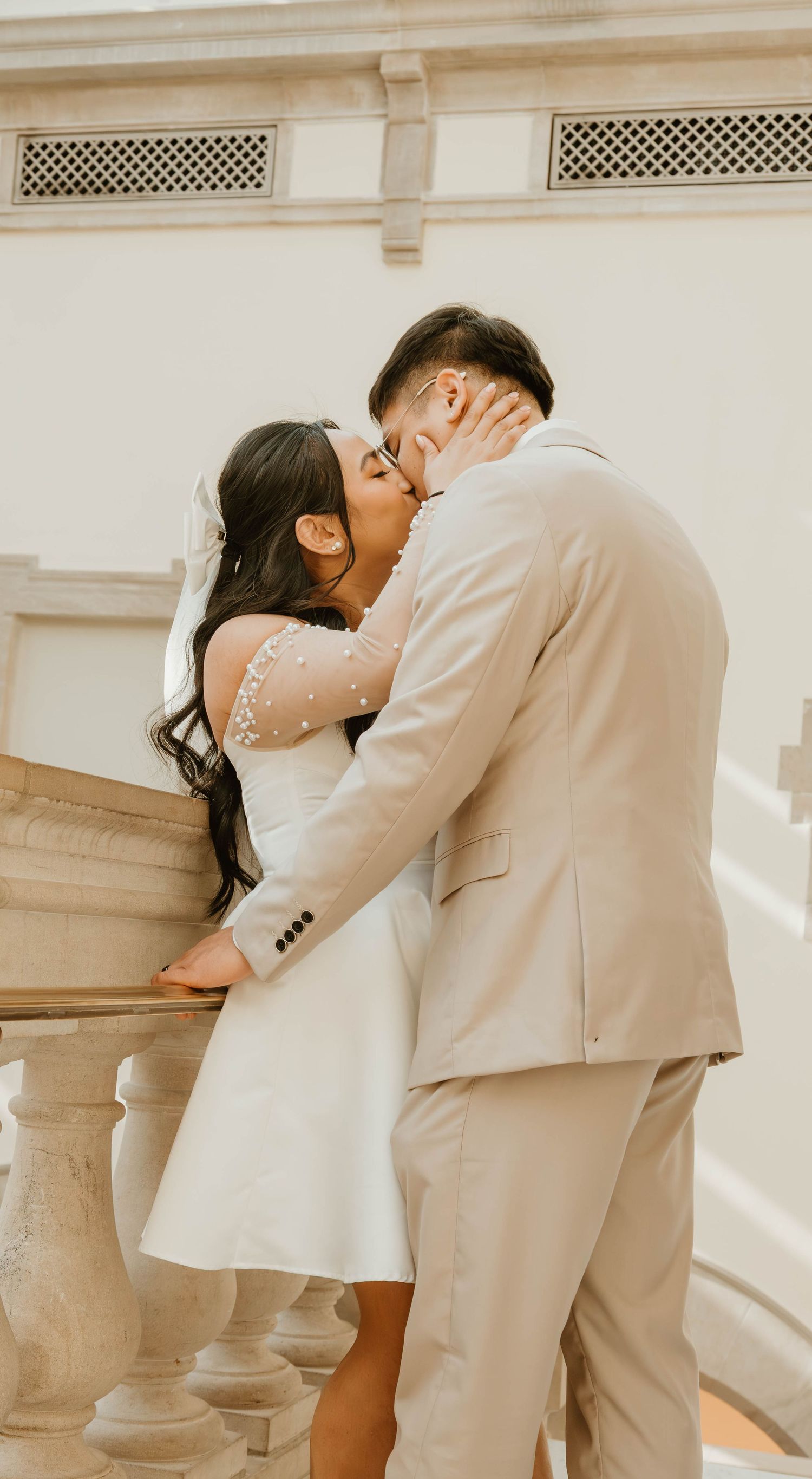 A bride and groom embrace and kiss in a romantic wedding setting.