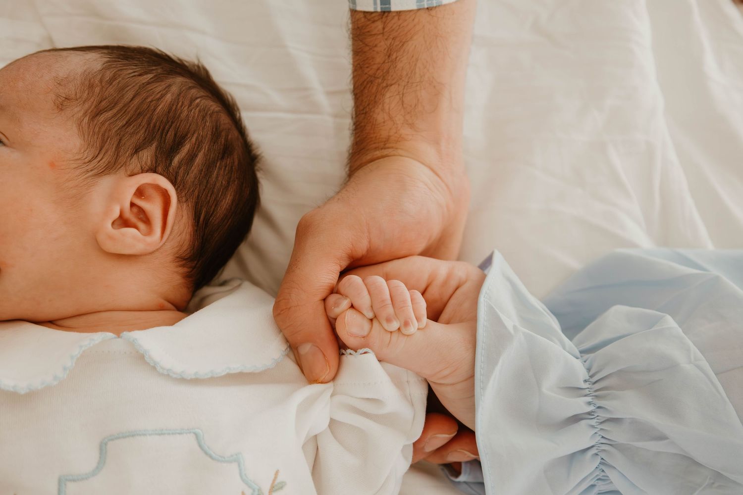 Newborn baby wrapped in white blanket lying on soft bedding.