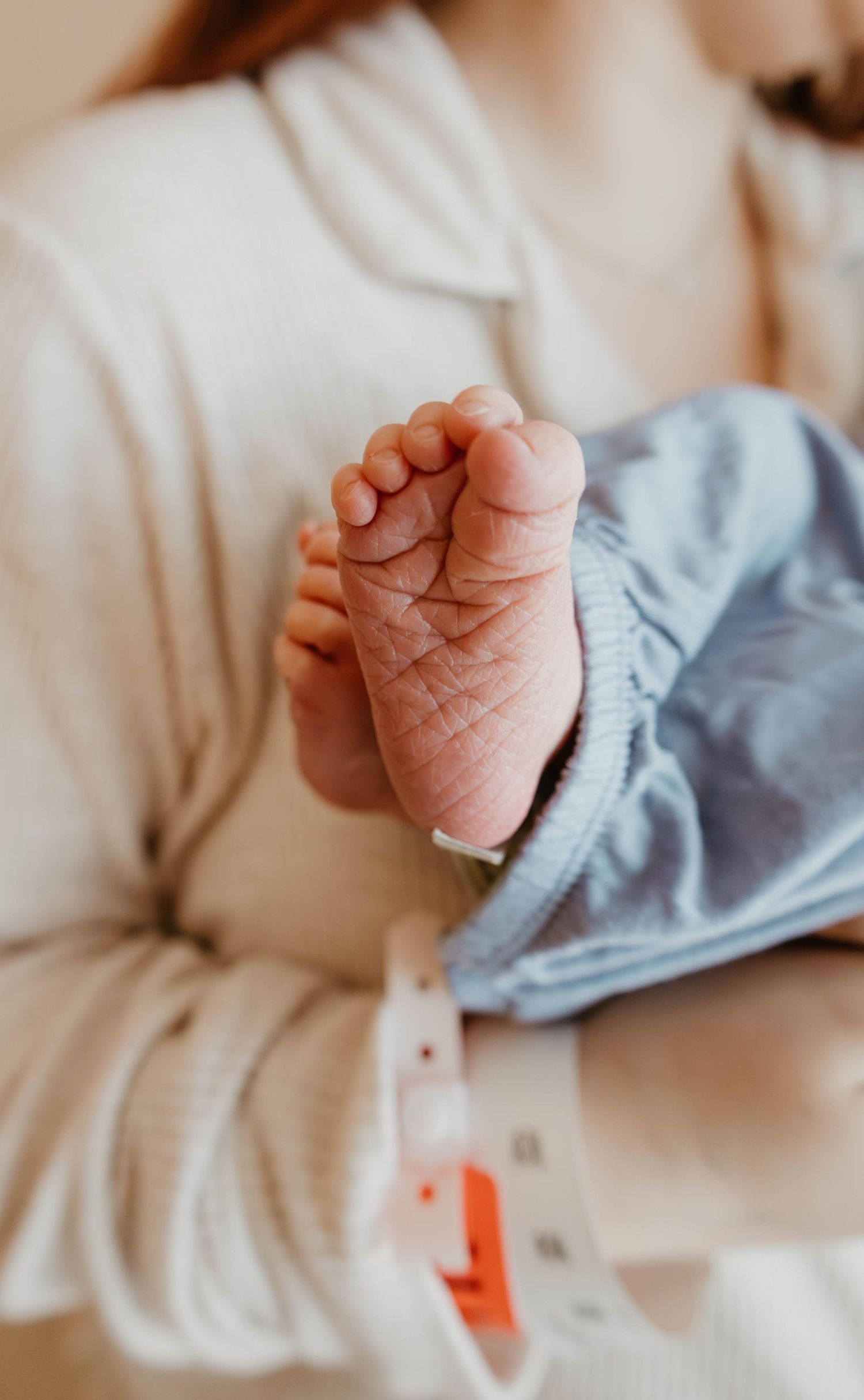 Close-up view of a tiny newborn baby foot against soft white and blue fabric.