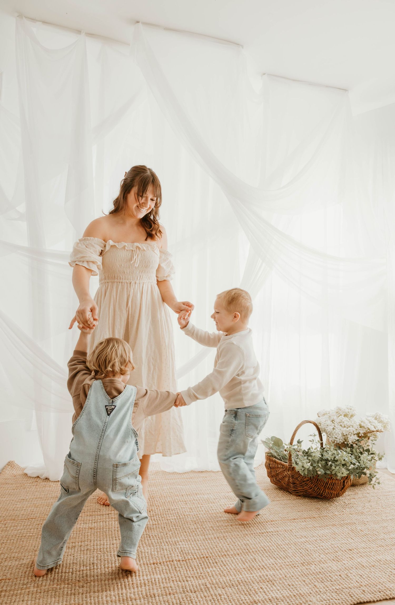 A sweet family moment captured in a series of candid dancing photos in a bright white studio setting.