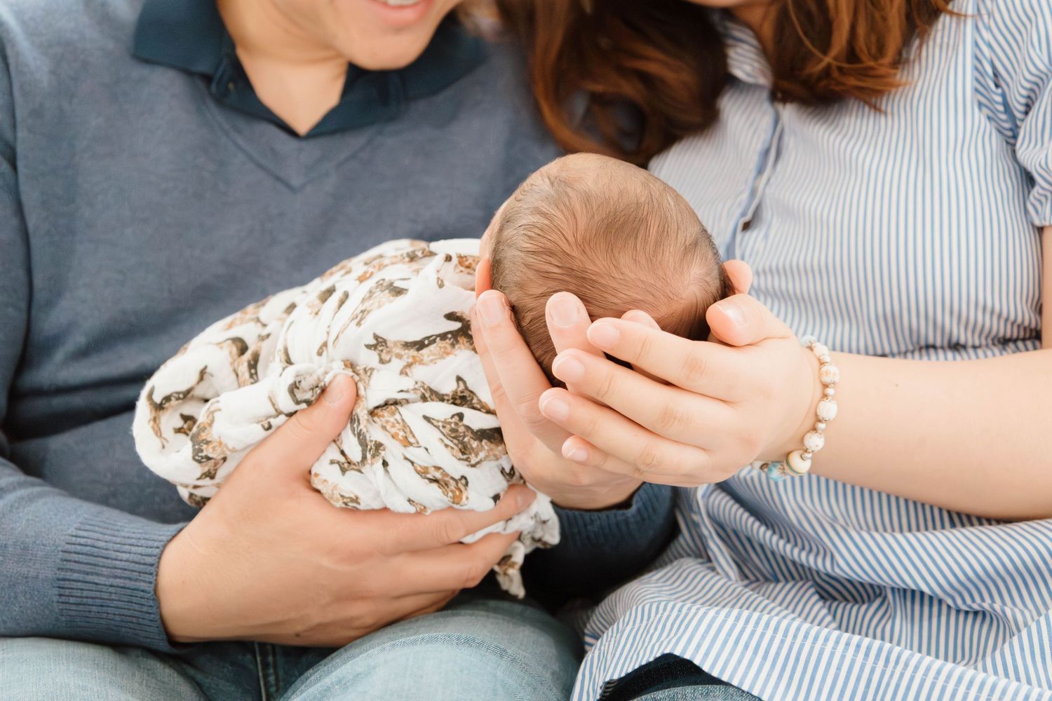 Close-up shots of parents cradling their newborn baby in casual home setting.