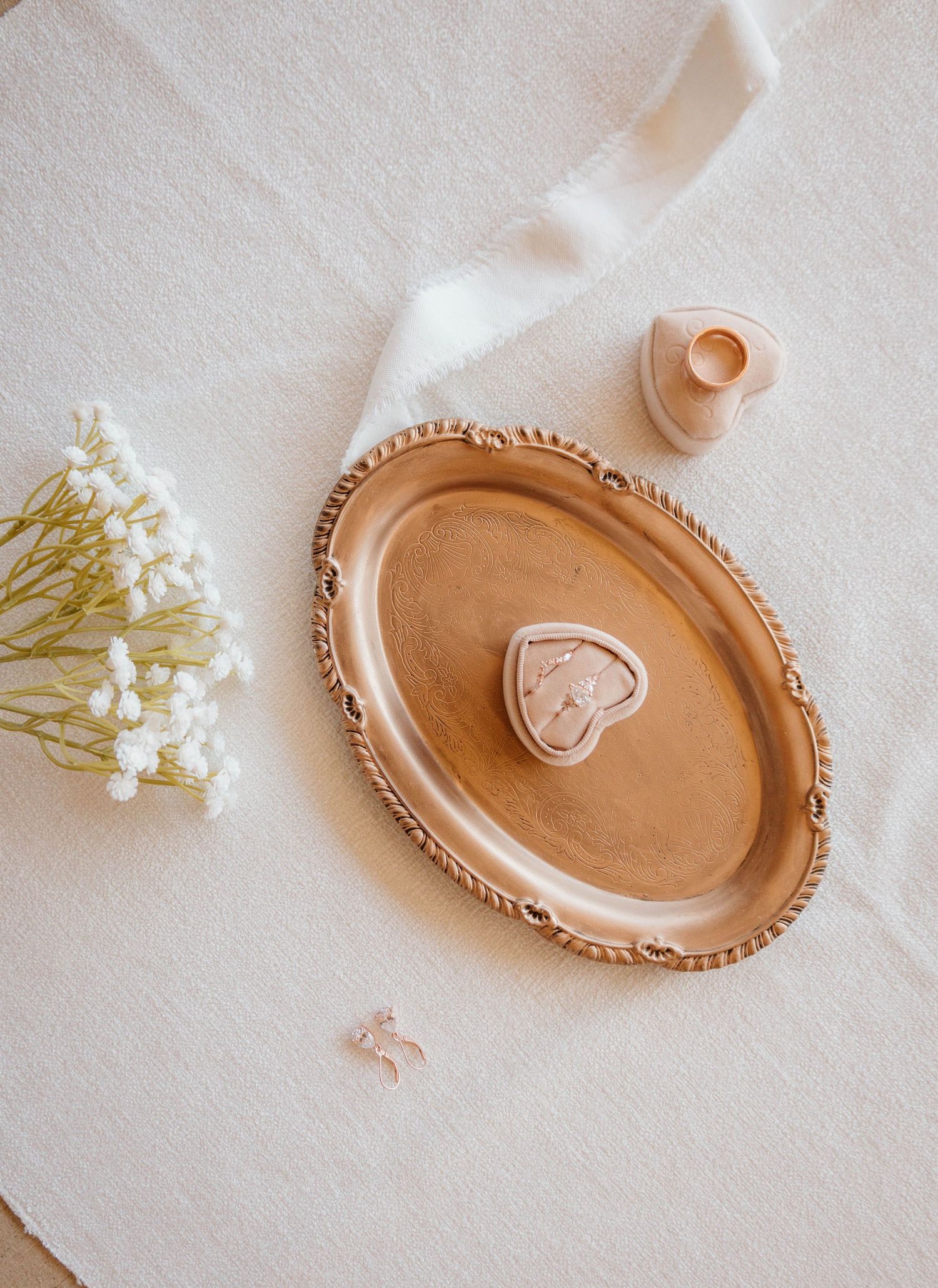 Rose gold decorative plate with heart design surrounded by white flowers and tulle.