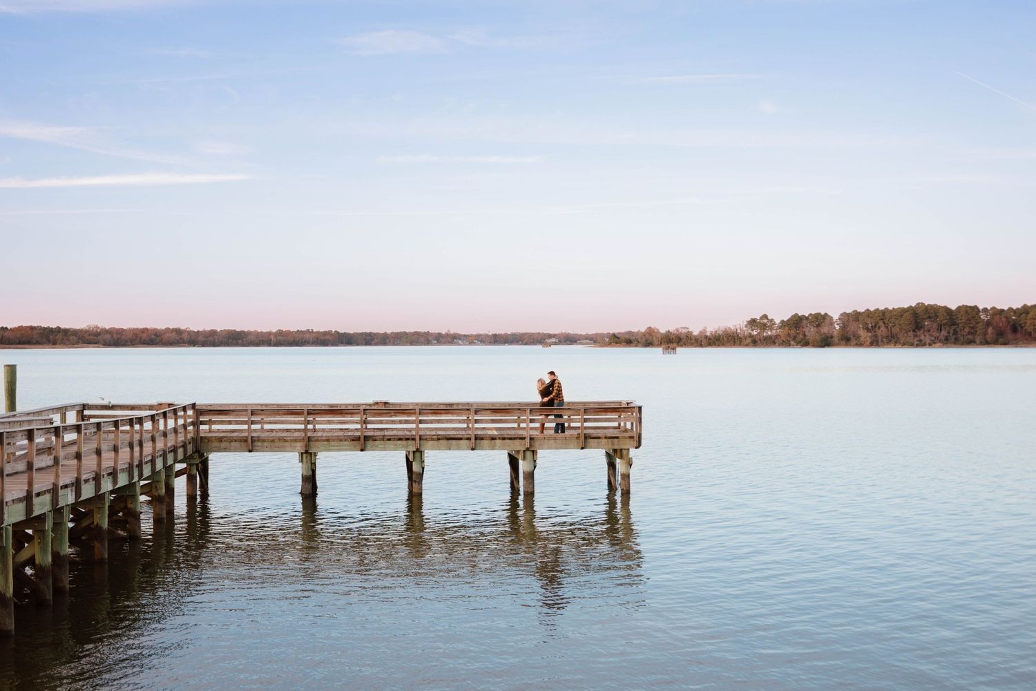 Peaceful wooden pier extending over calm waters during sunset.