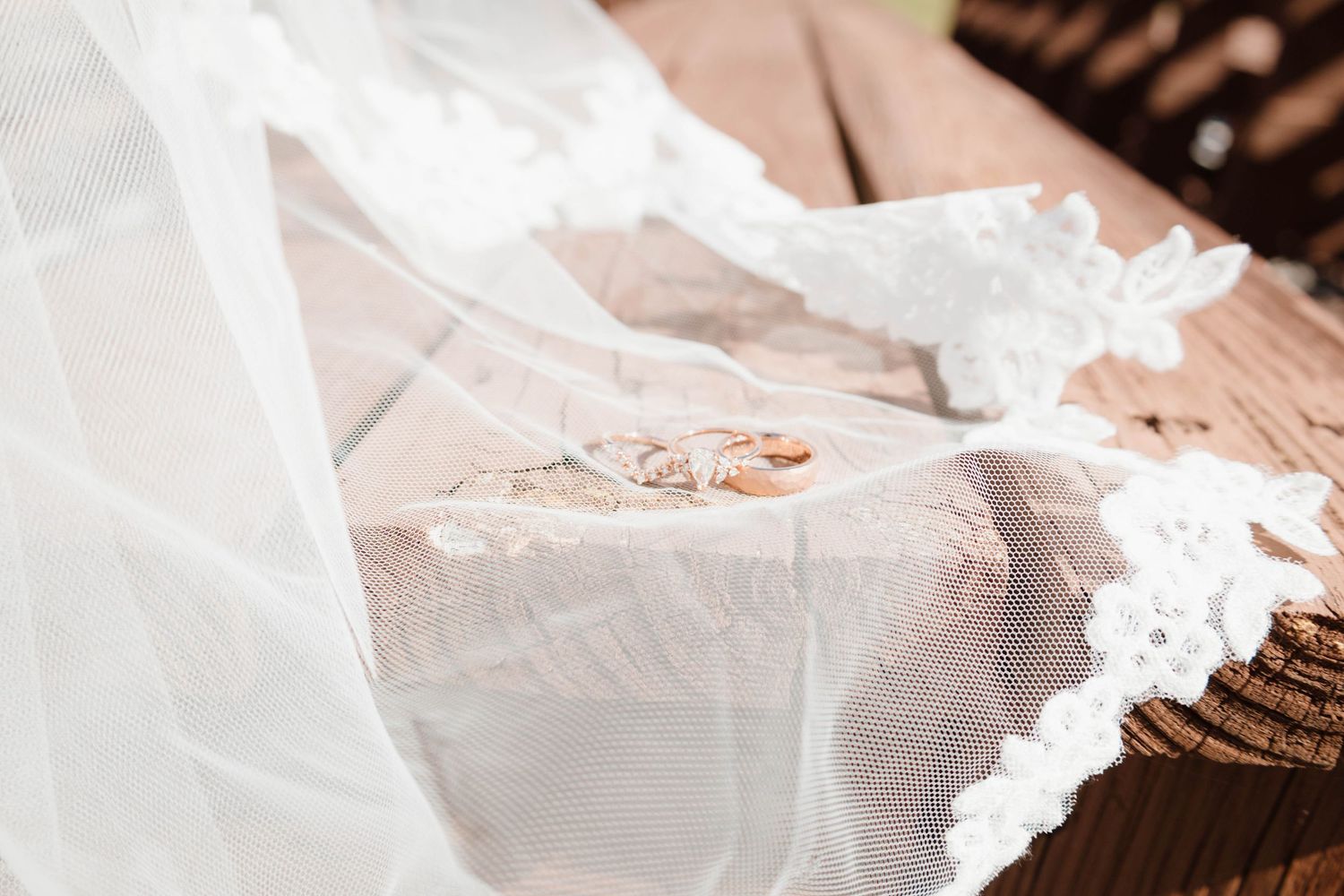 Wedding rings and lace details captured on a wooden surface.