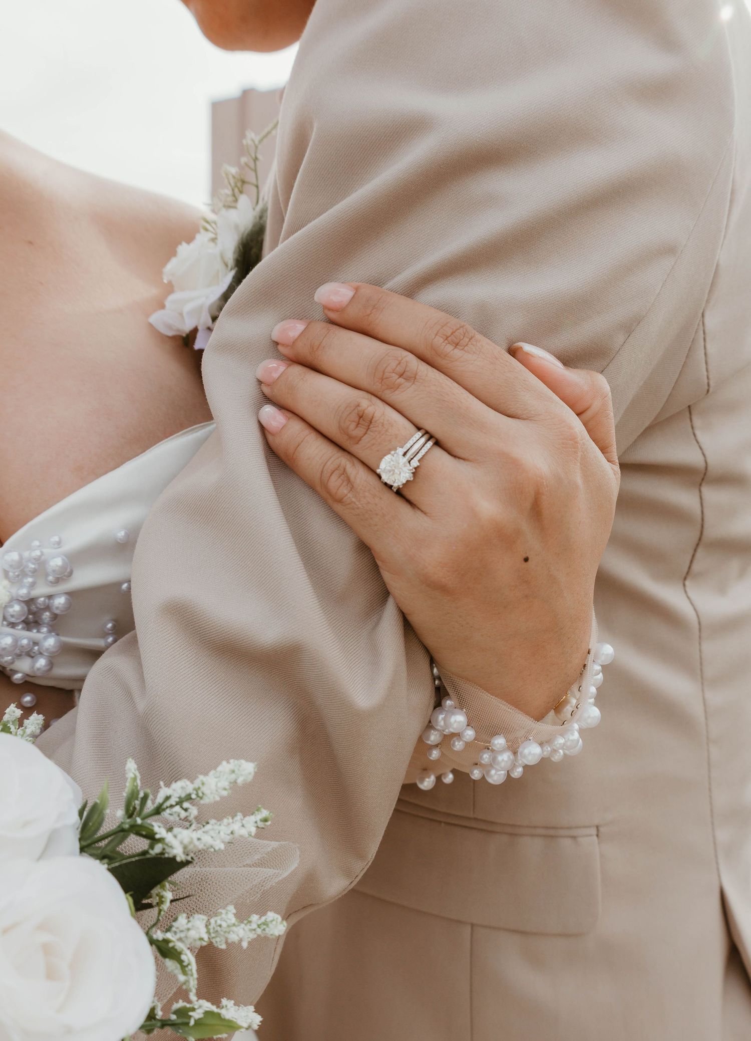 A close-up view of a bride and groom's hands, with the bride's hand wearing a wedding ring.