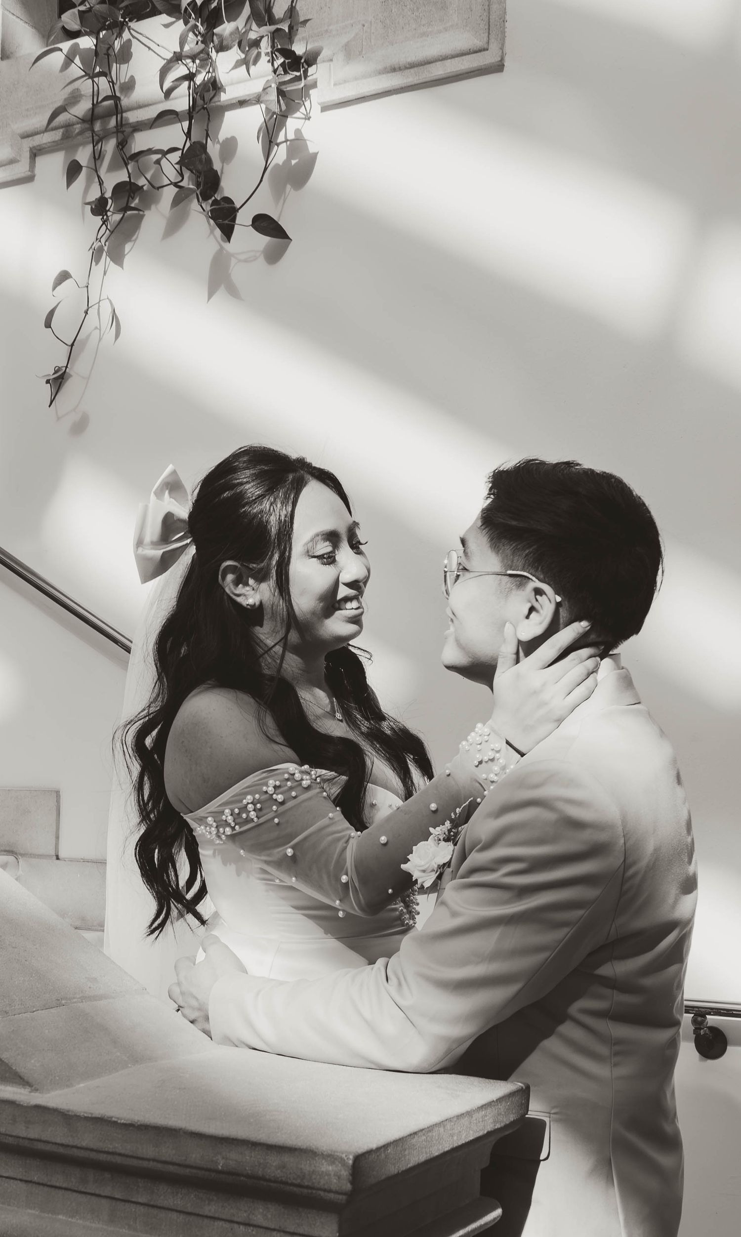 A black and white image showing a couple embracing and gazing at each other in an intimate moment.