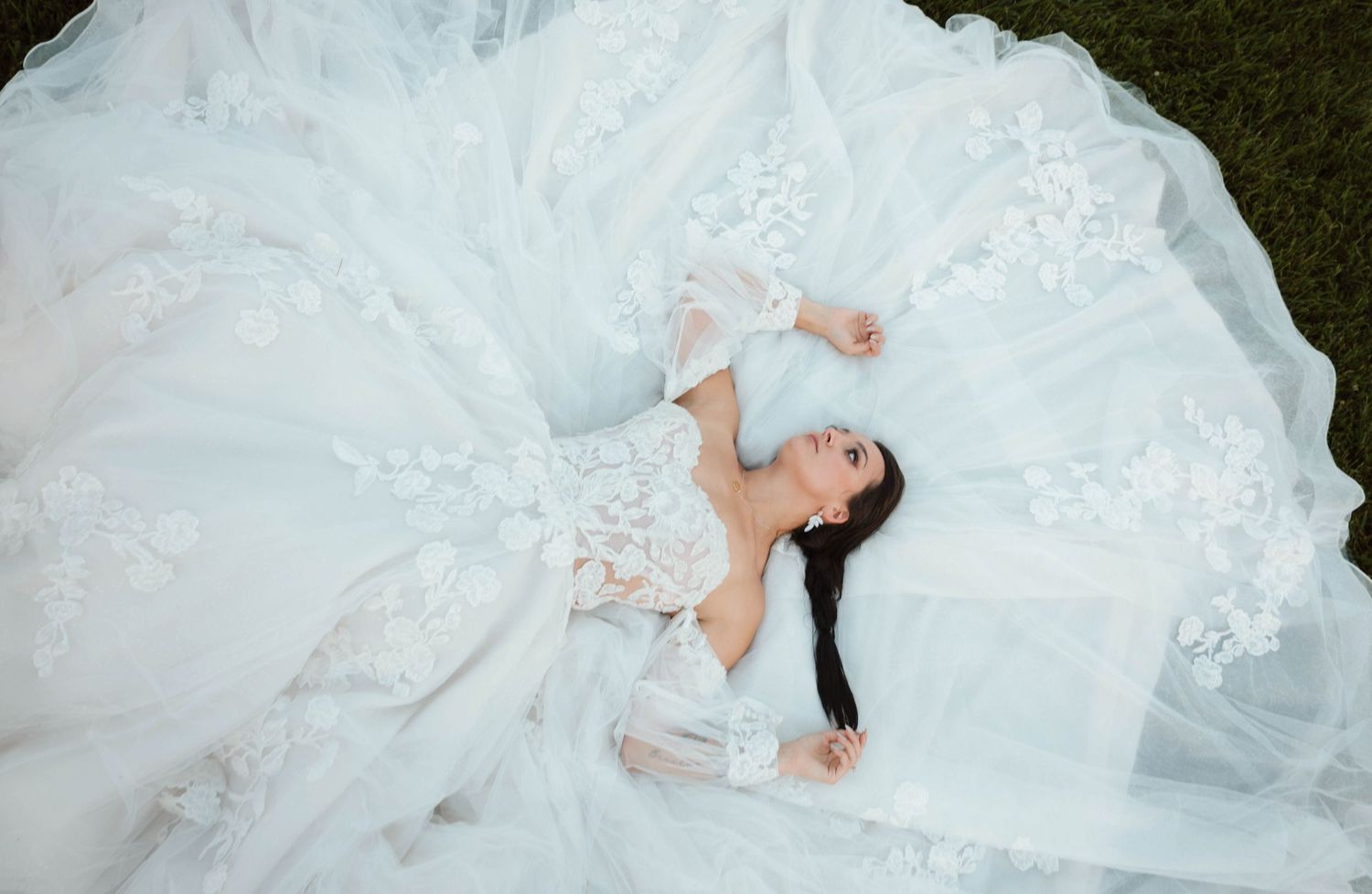 Artistic overhead shots of a bride in white lace dress laying on grass.