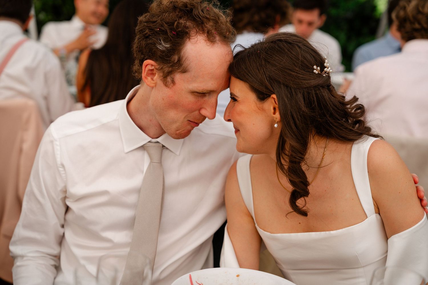 A bride and groom share an intimate moment leaning foreheads together at their wedding reception.