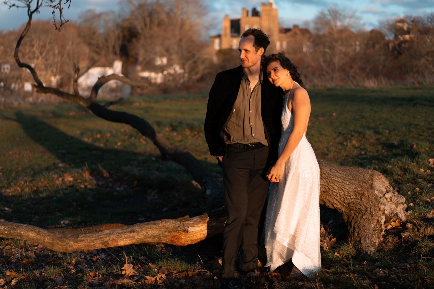 A couple poses together near a fallen log during a sunset photography session.