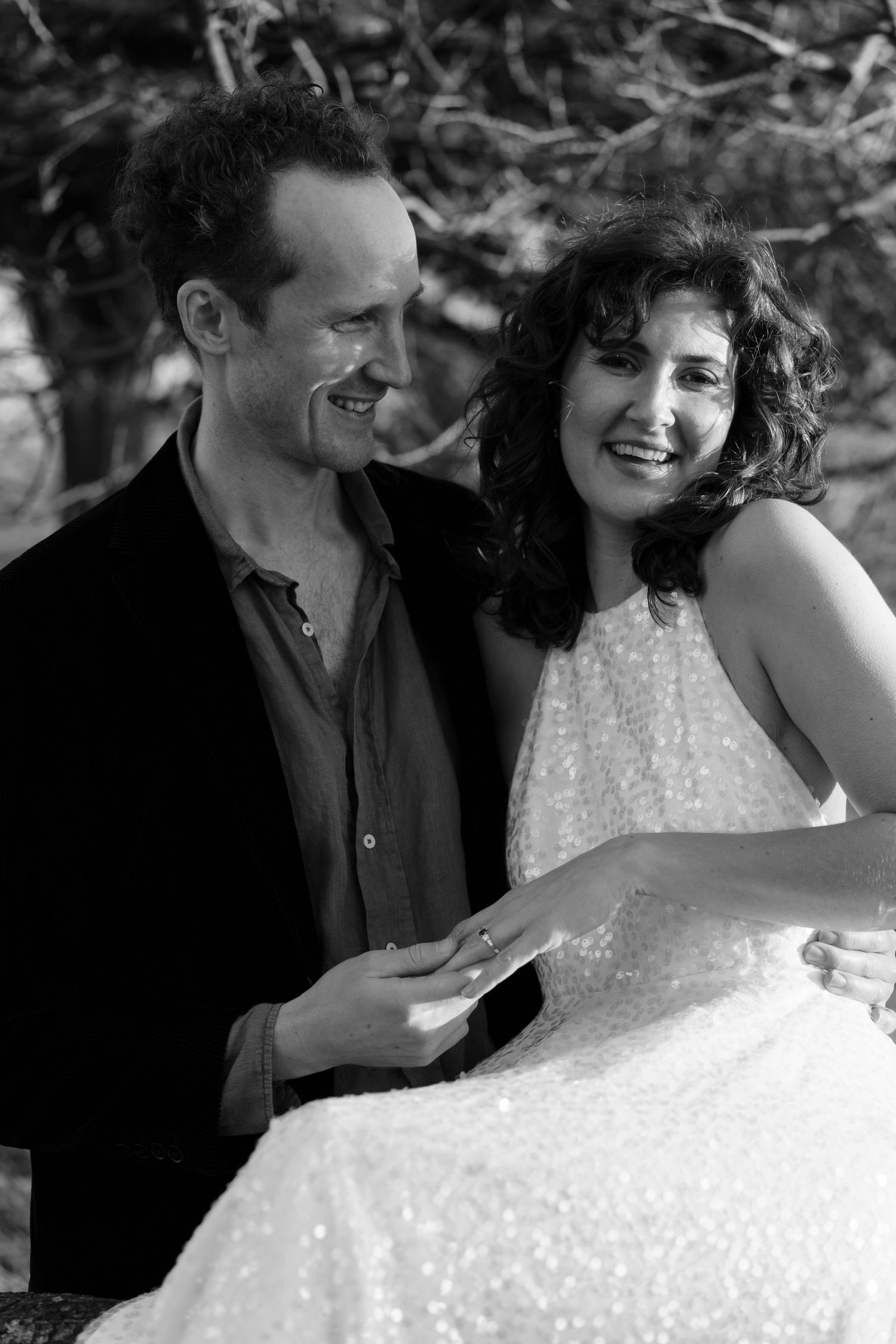 Black and white portrait captures couple's laughter during outdoor photoshoot.