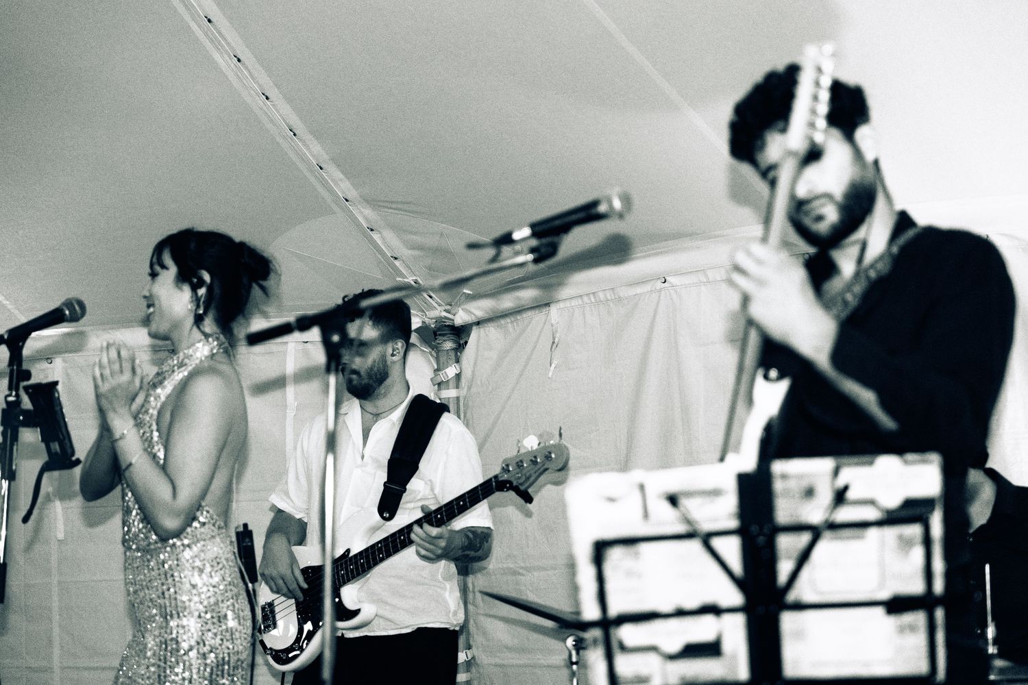 Black and white photo of a live band performing, featuring a female singer and guitarist at a wedding reception.