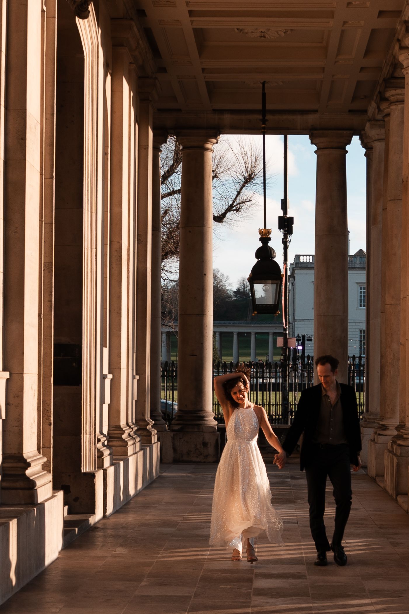 Elegant figures moving through a classical colonnade with dramatic lighting.