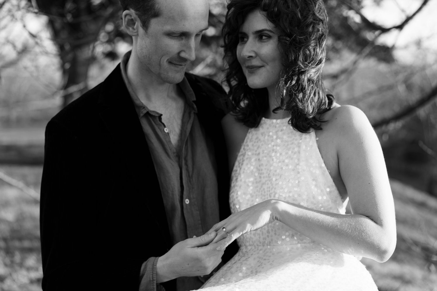 A romantic black and white portrait of a couple sharing an intimate moment while reading together outdoors.