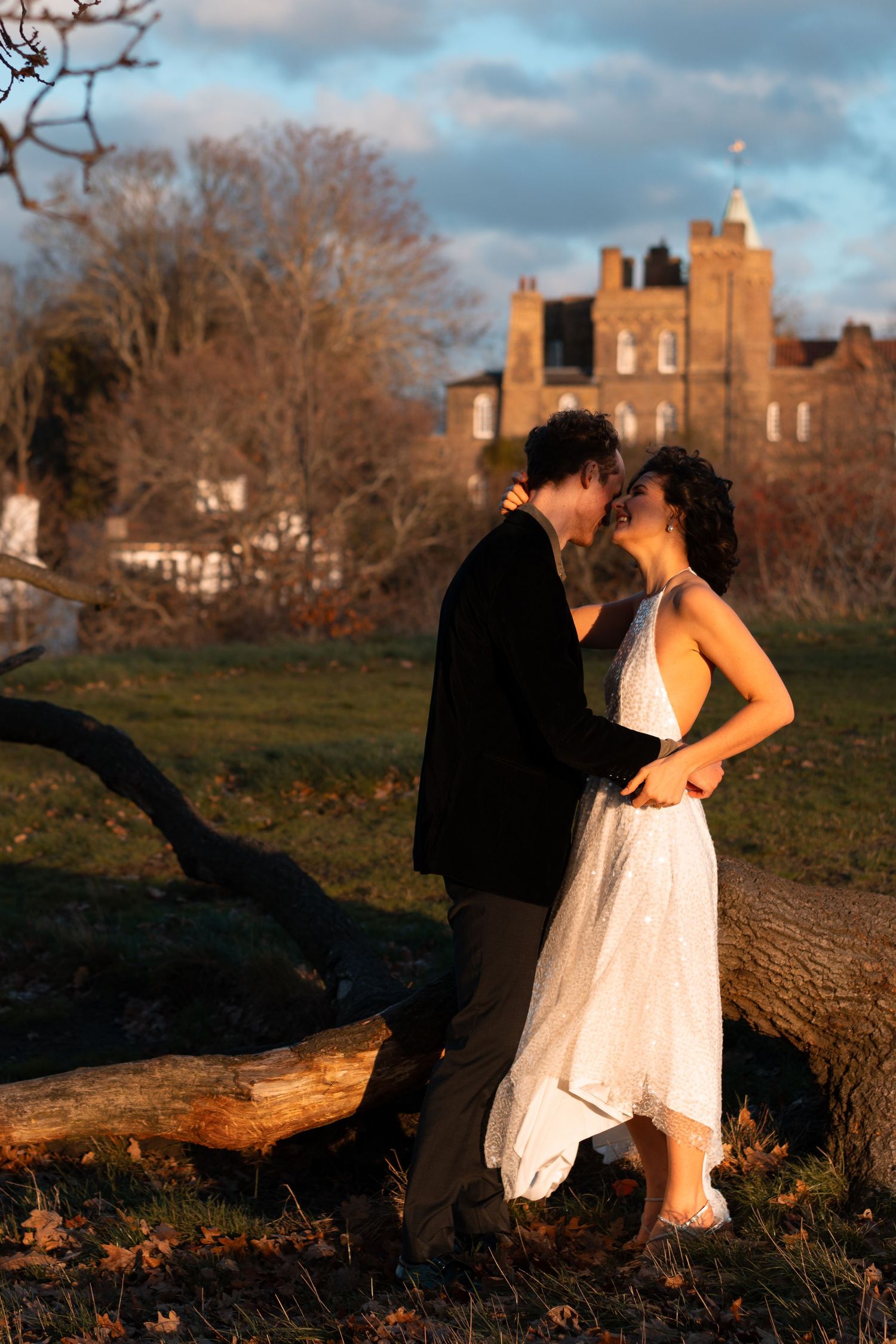 A couple shares an intimate moment on a fallen tree trunk during golden hour.