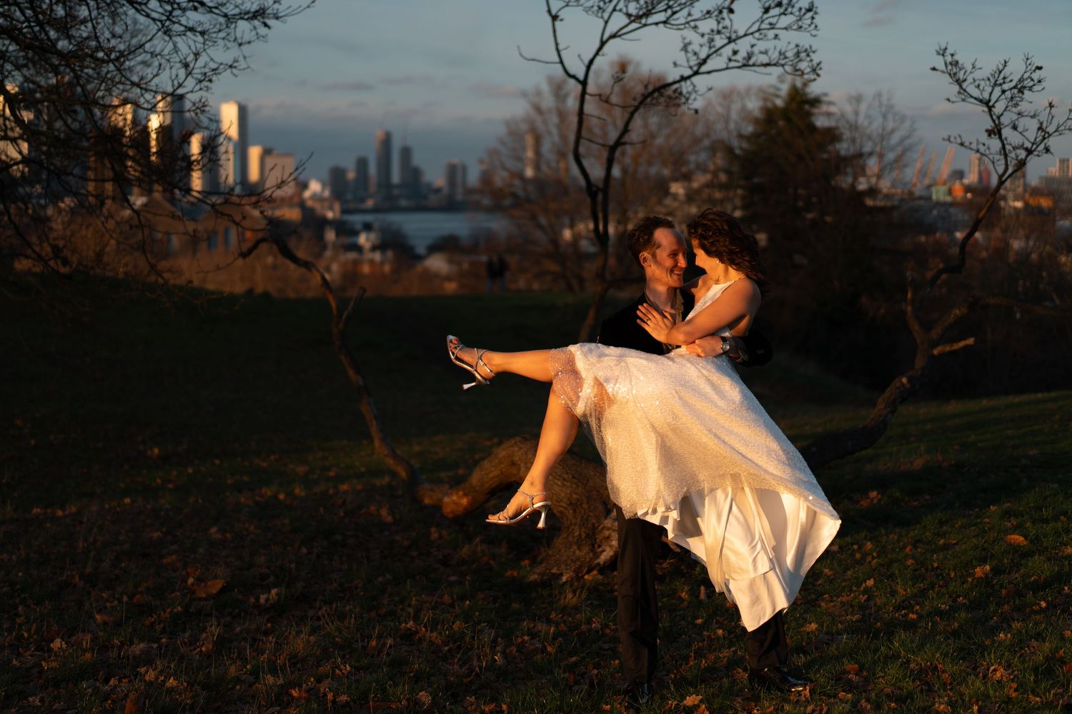 An elegant dance pose silhouetted against the setting sun with city buildings in the distance.