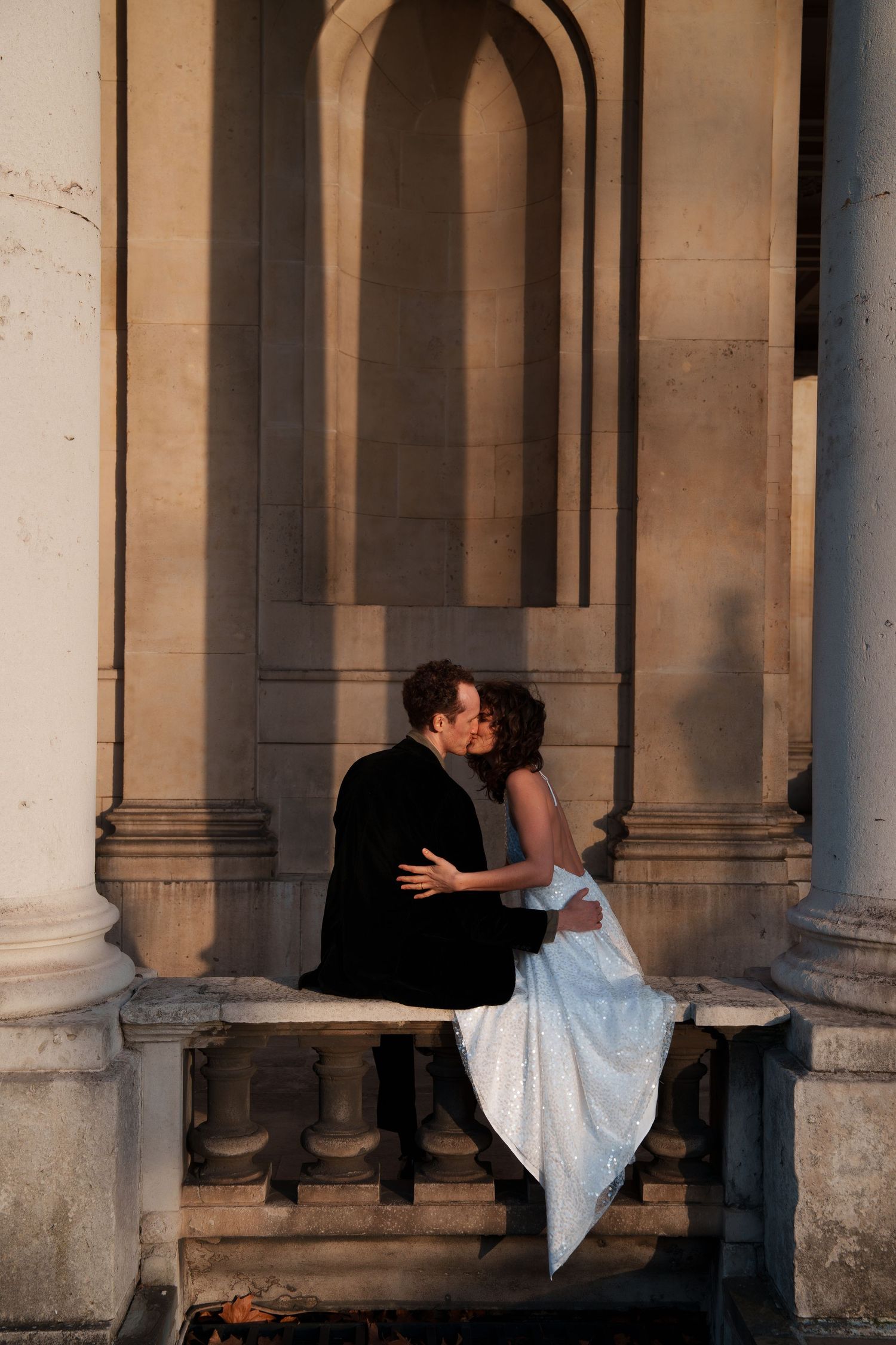 Romantic dance pose captured in the shadows of a grand colonnade.