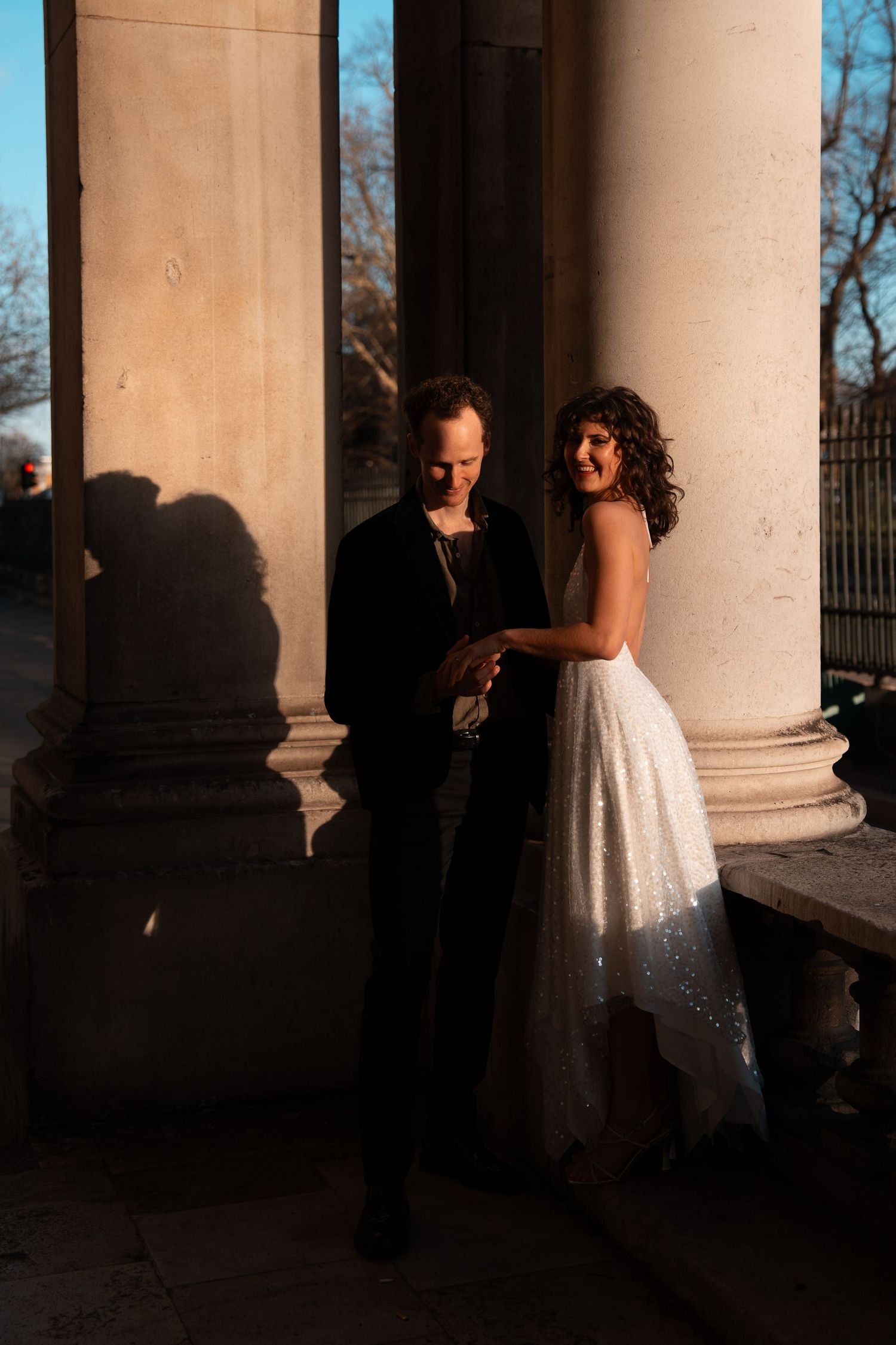 Golden hour light creates dramatic shadows as dancers move through a classical colonnade.