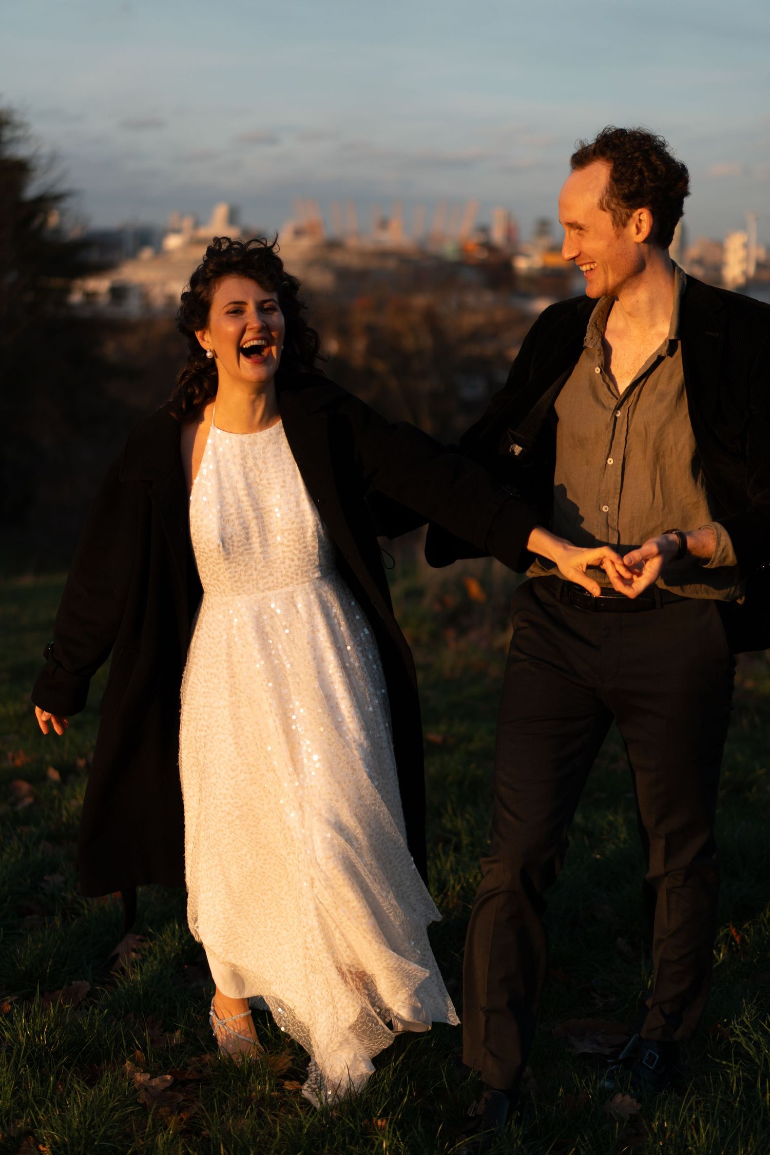 Dancers in contrasting white and dark outfits move expressively against sunset city views.