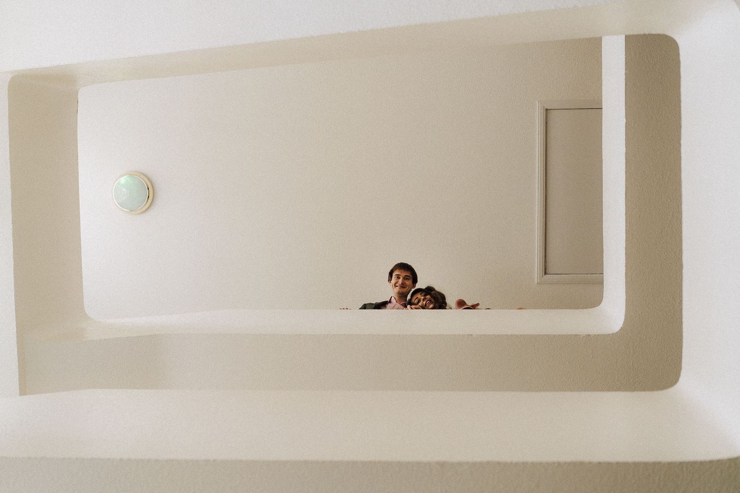 Contemporary white interior with architectural cutouts and small figures visible through openings.