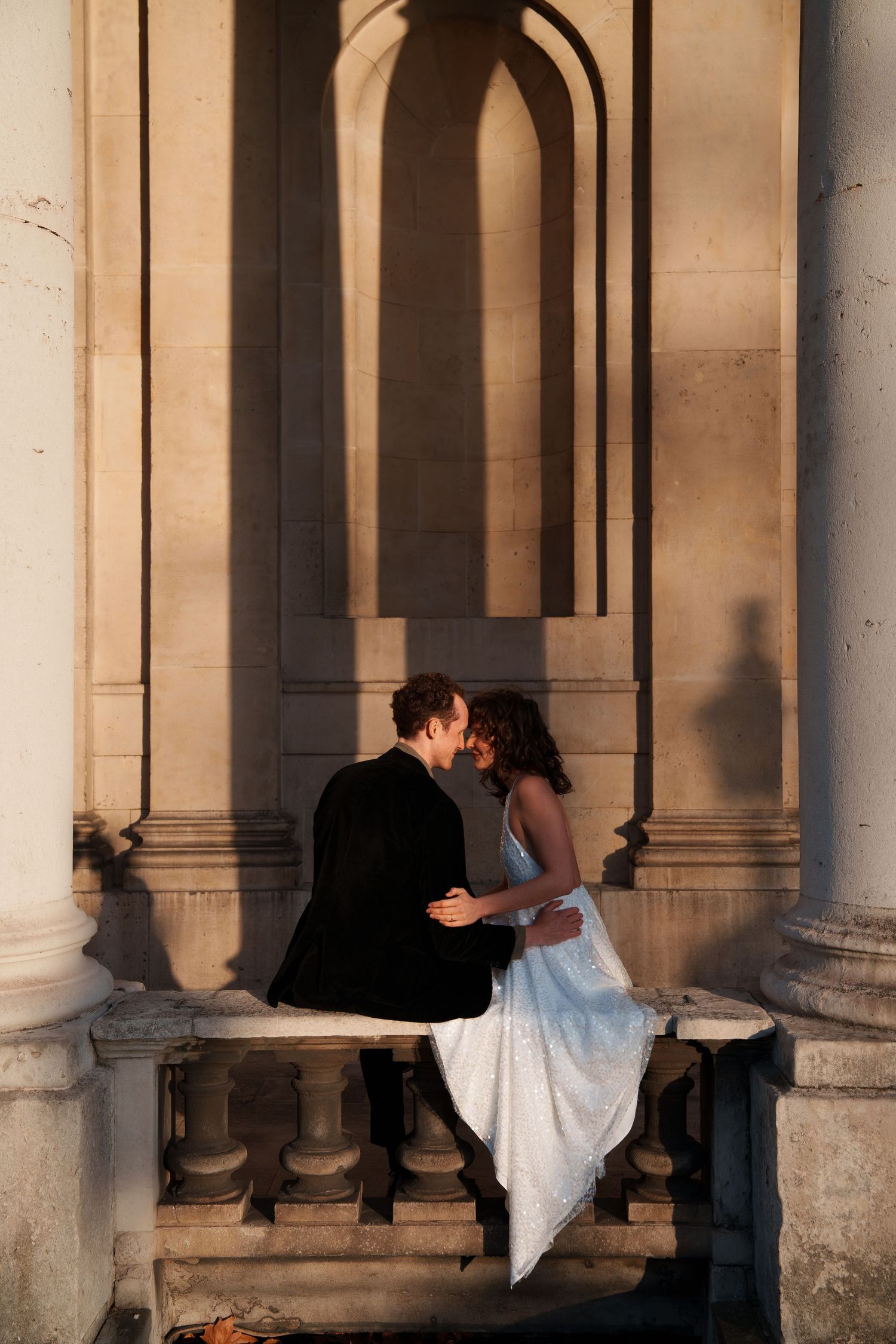 Dancers perform in the shadows of an elegant colonnade with warm evening light.