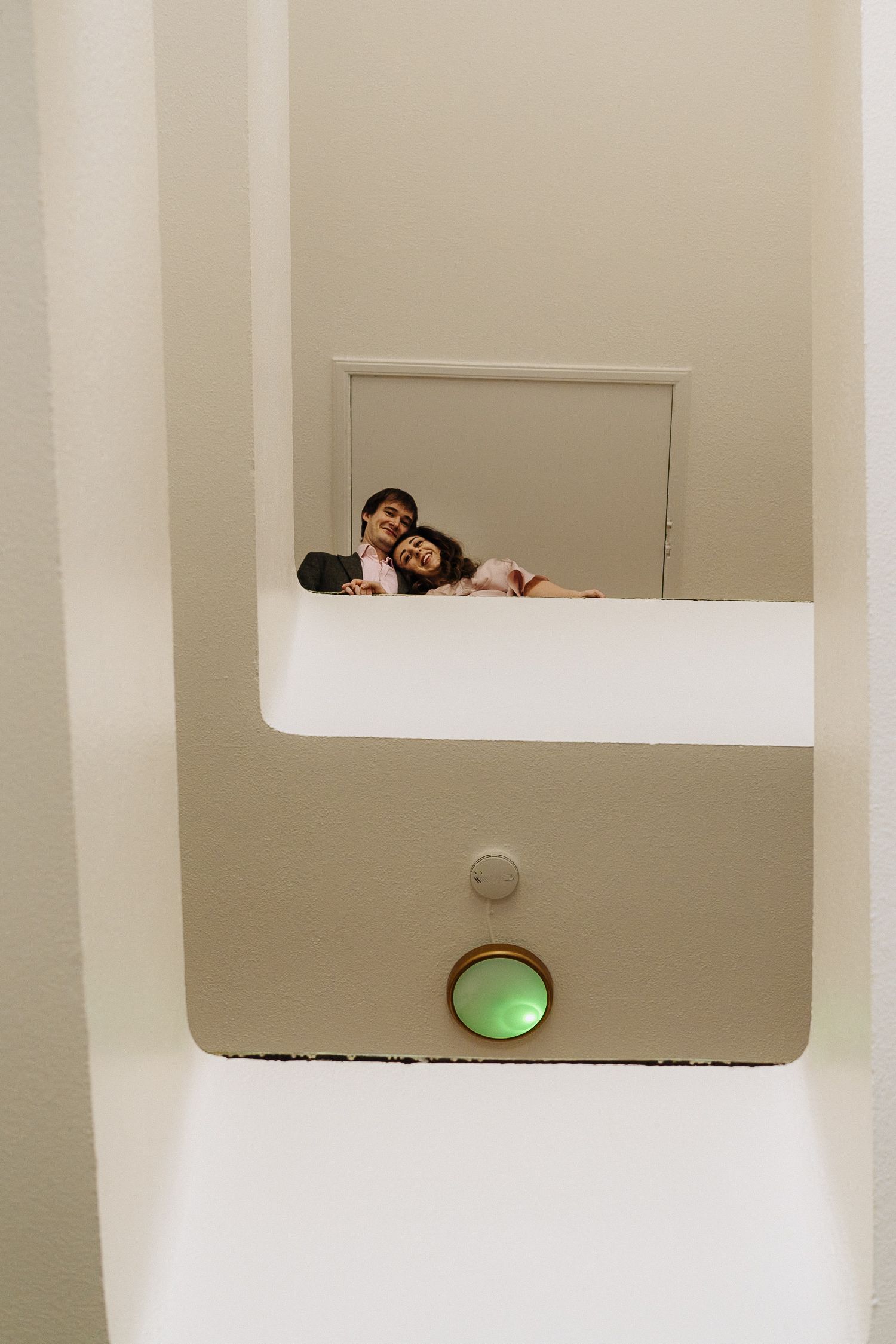 Modern white interior space with geometric cutouts and a green circular light visible in the distance.