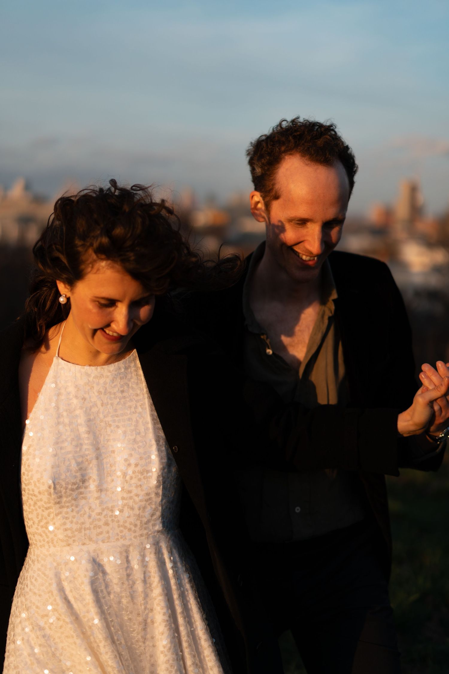 A couple dances together at sunset with a city skyline visible in the background.