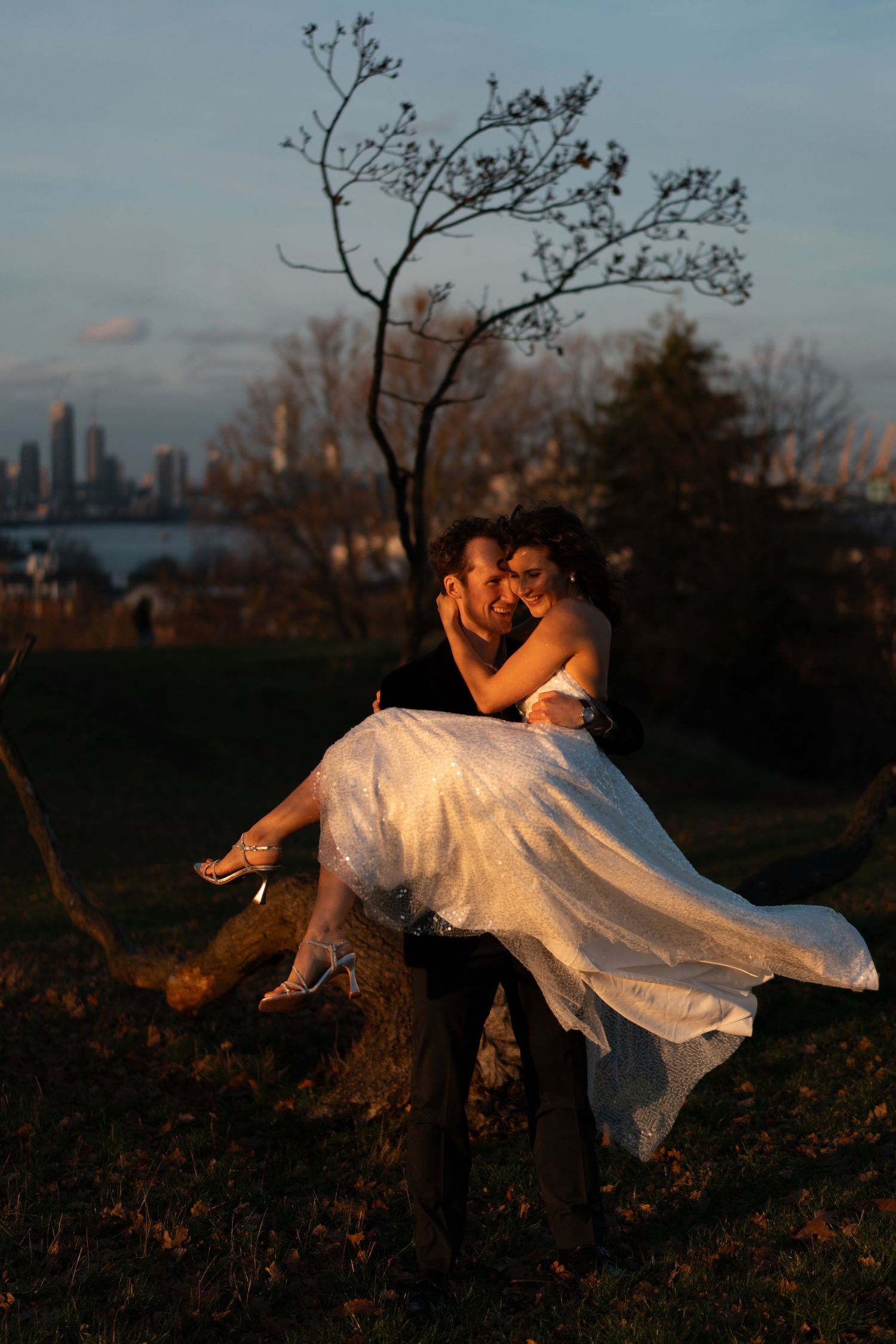 A flowing white dress catches the evening light as a couple shares an intimate moment on a hilltop.