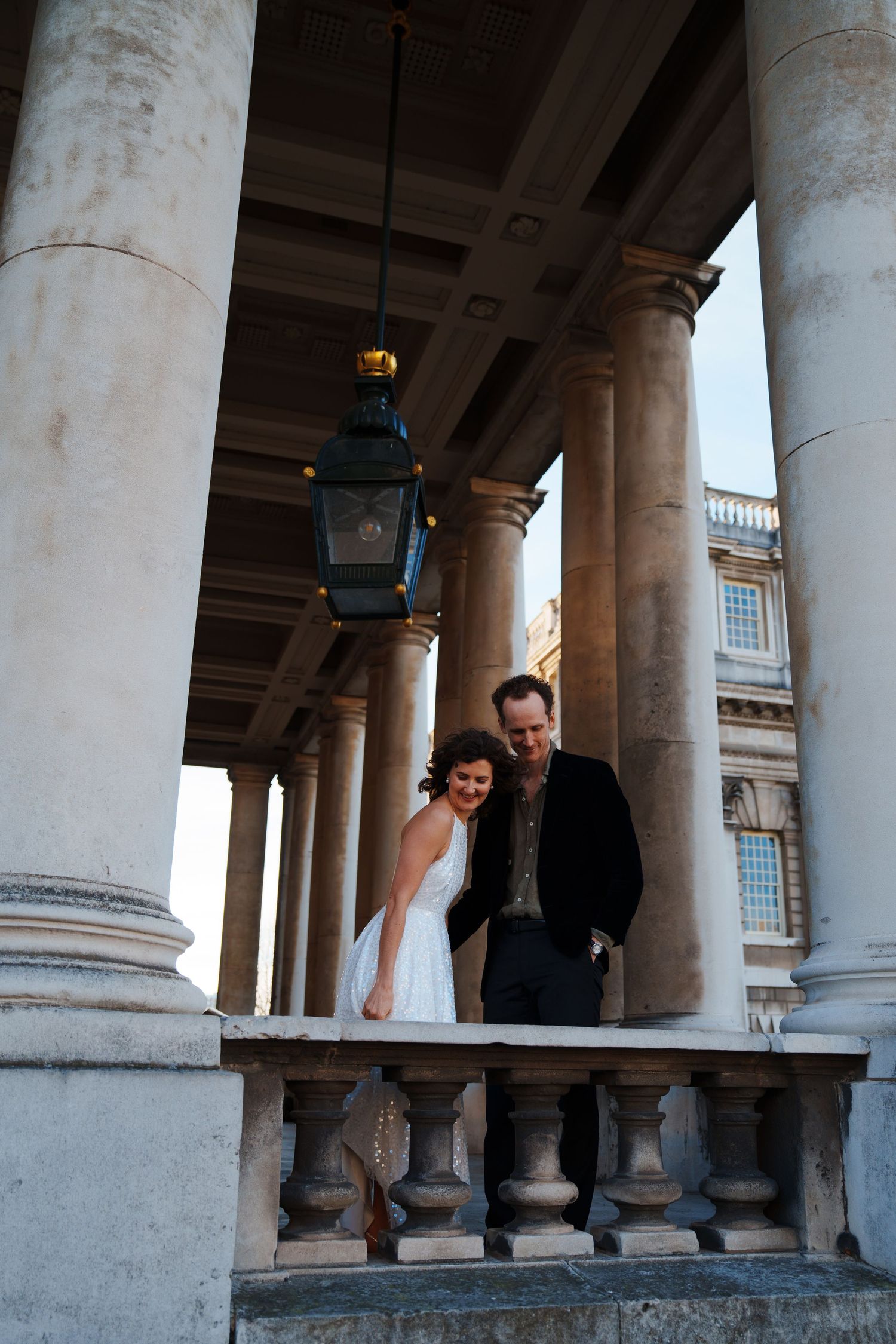A couple explores a historic colonnade with stone pillars.